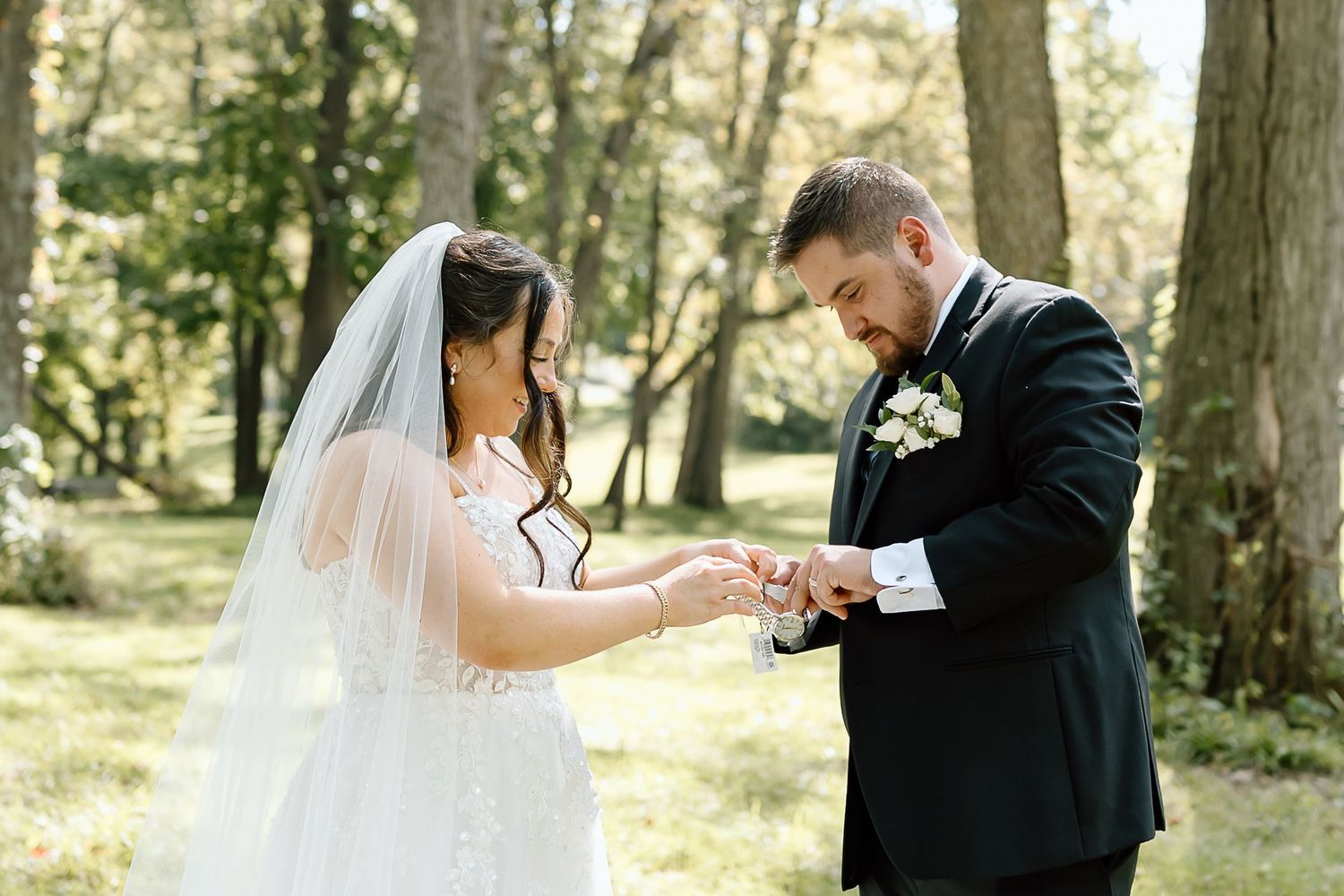 A romantic wedding photoshoot in a sunlit forest with a couple in traditional wedding attire sharing intimate moments.