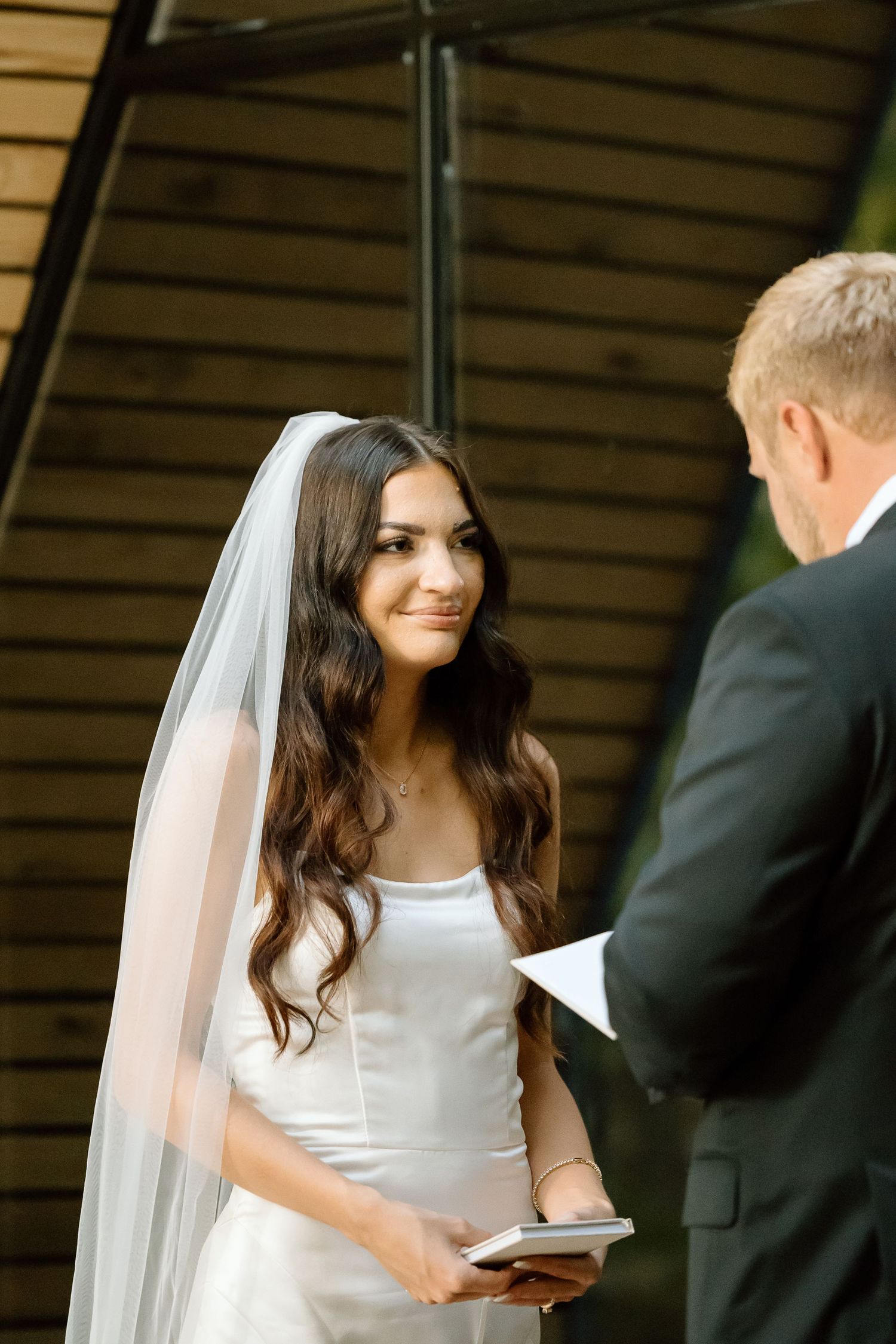 A bride in a white dress and veil shares a tender moment during a wedding ceremony.