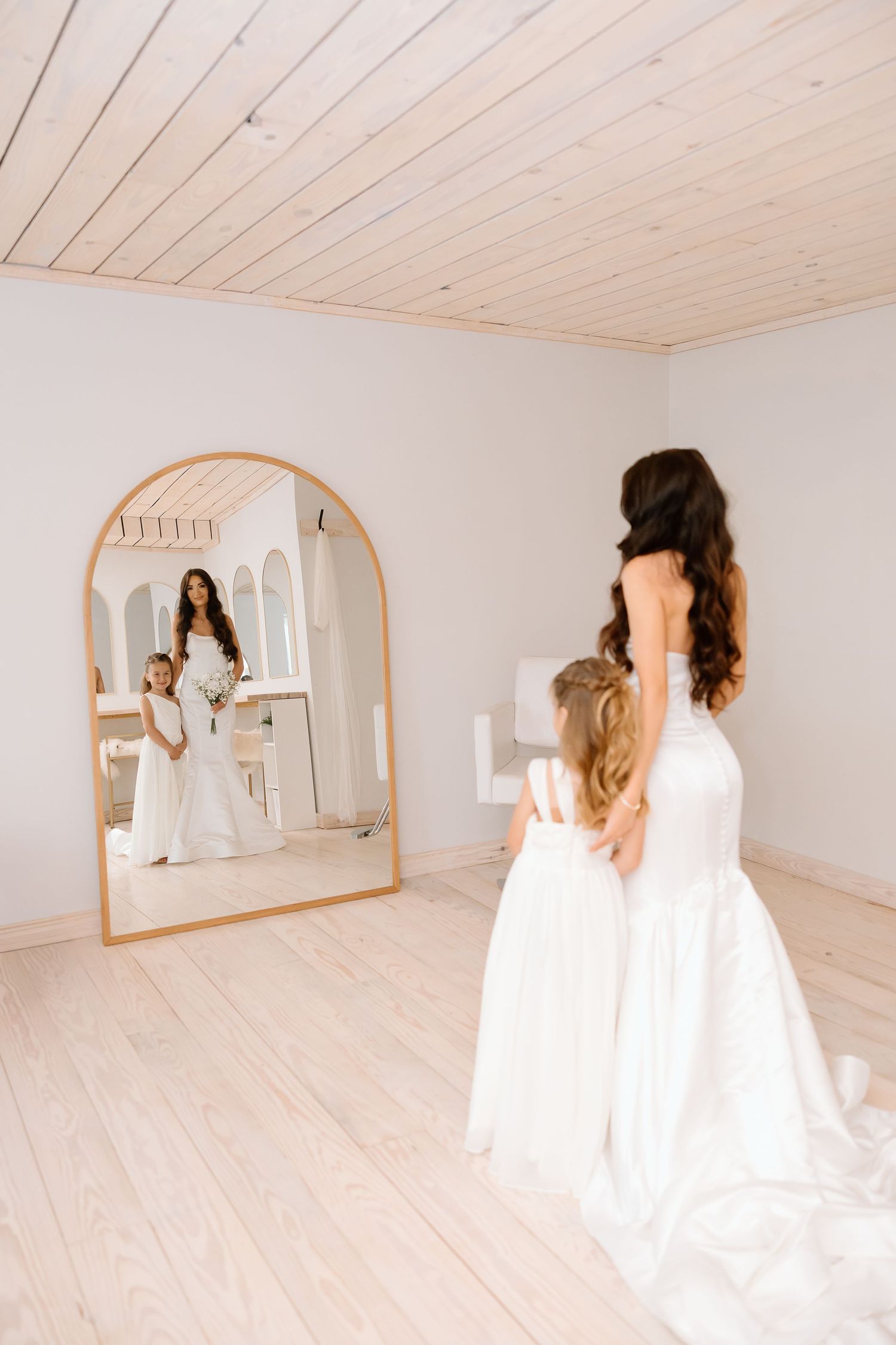 Light and airy bridal suite with white walls, wood ceiling, and large mirror showcases elegant wedding preparations.