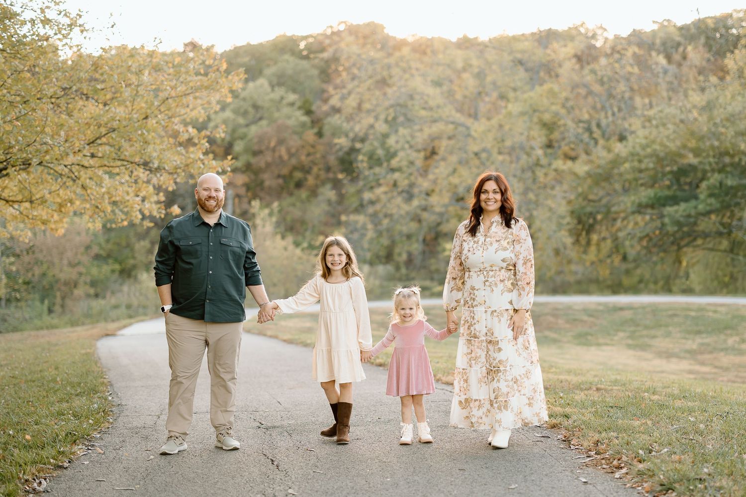 A group walks together on a scenic autumn path during golden hour with trees and foliage in the background.