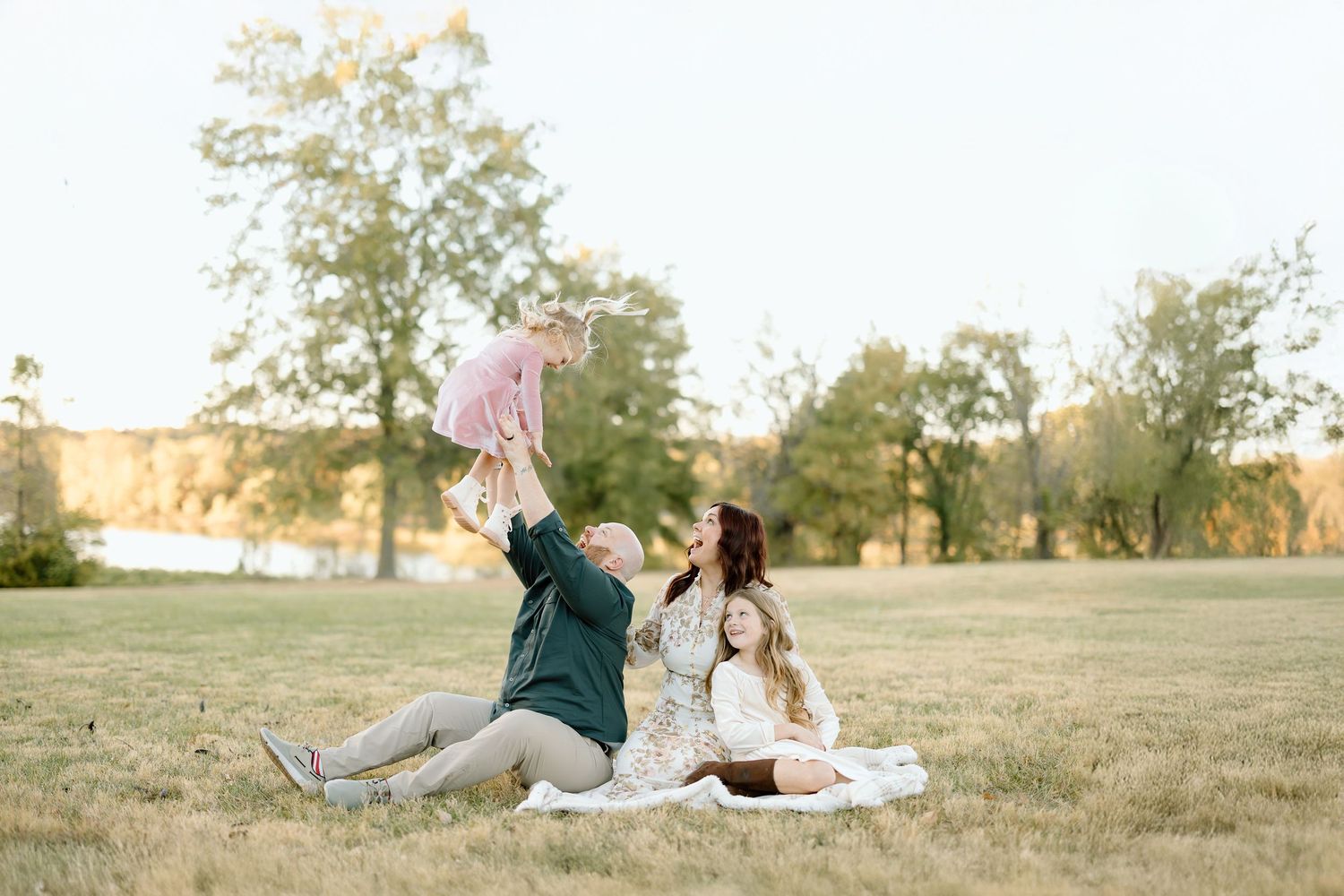 Couple enjoying a romantic sunset picnic on a grassy hill with blankets and snacks.