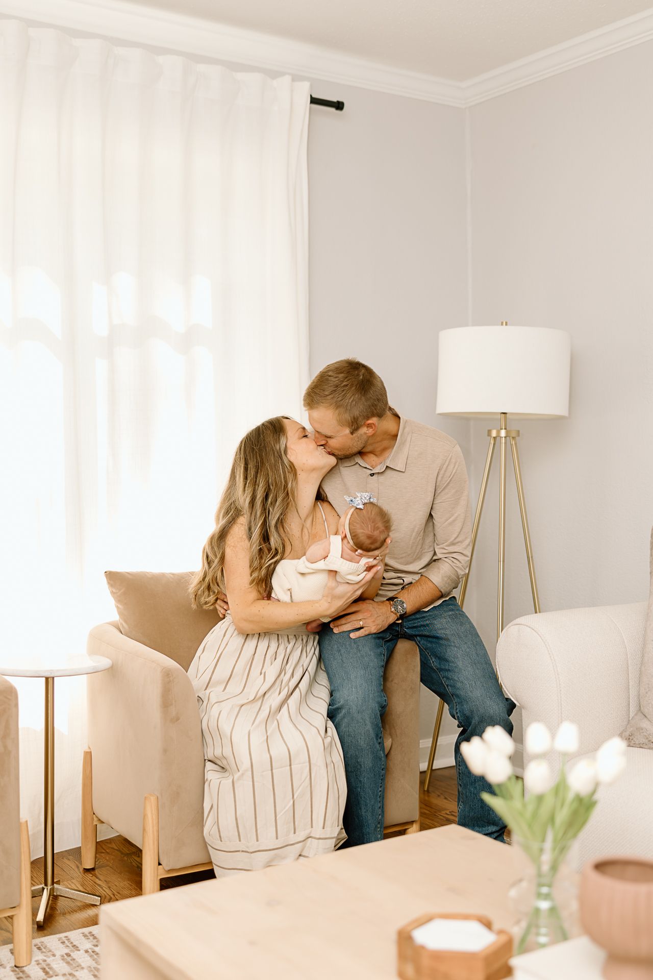 Intimate family portrait in well-lit living room with modern furniture and white curtains.