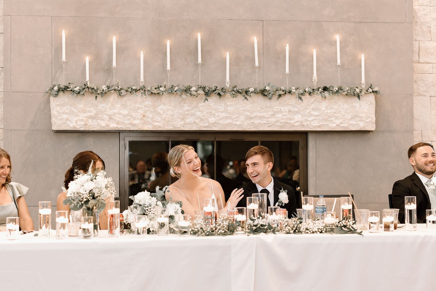 A decorative wedding reception setup with elegant table settings and hanging string lights in a modern venue.