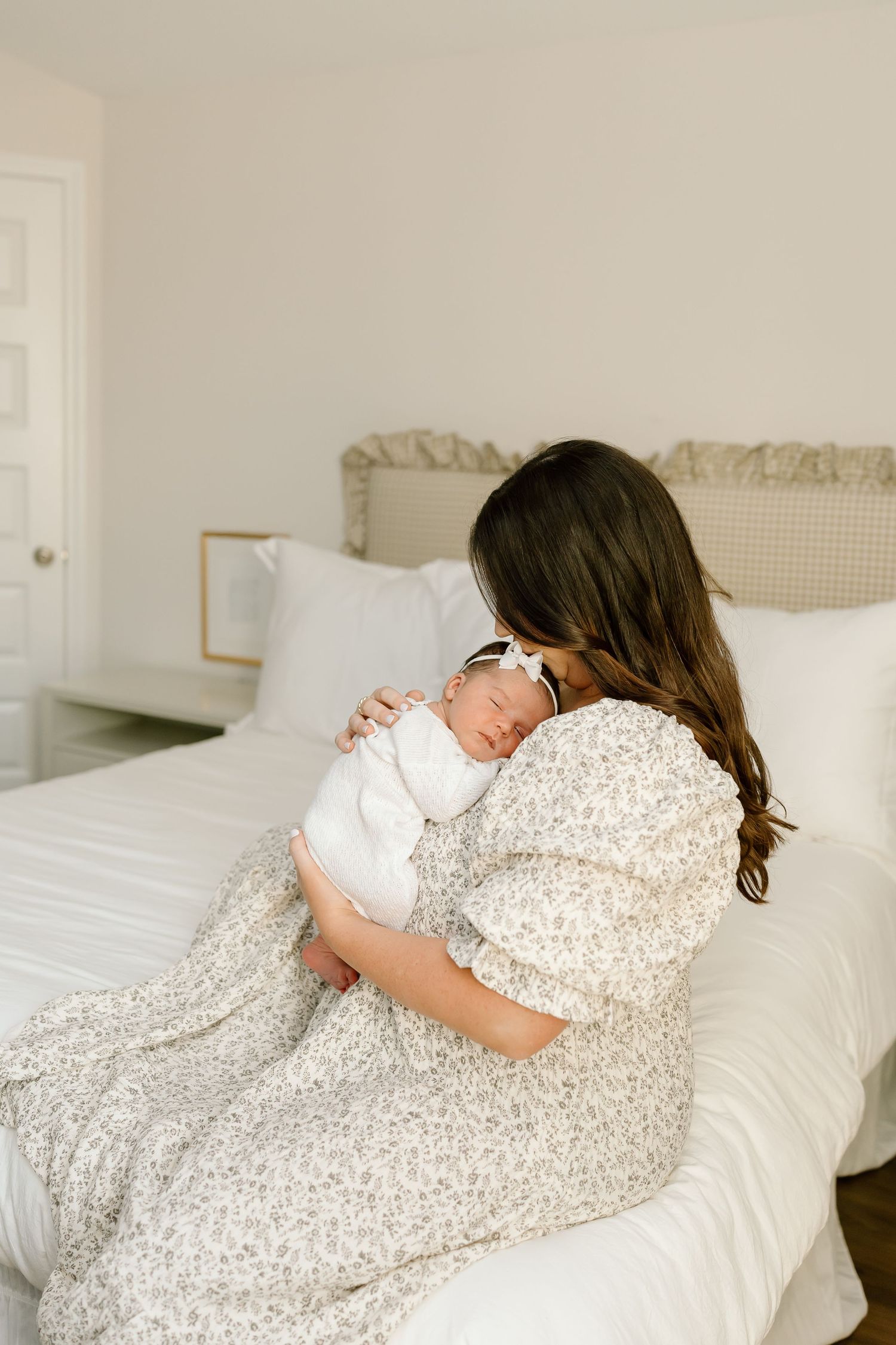 A peaceful scene showing parent and baby resting together on a white bed with floral bedding.