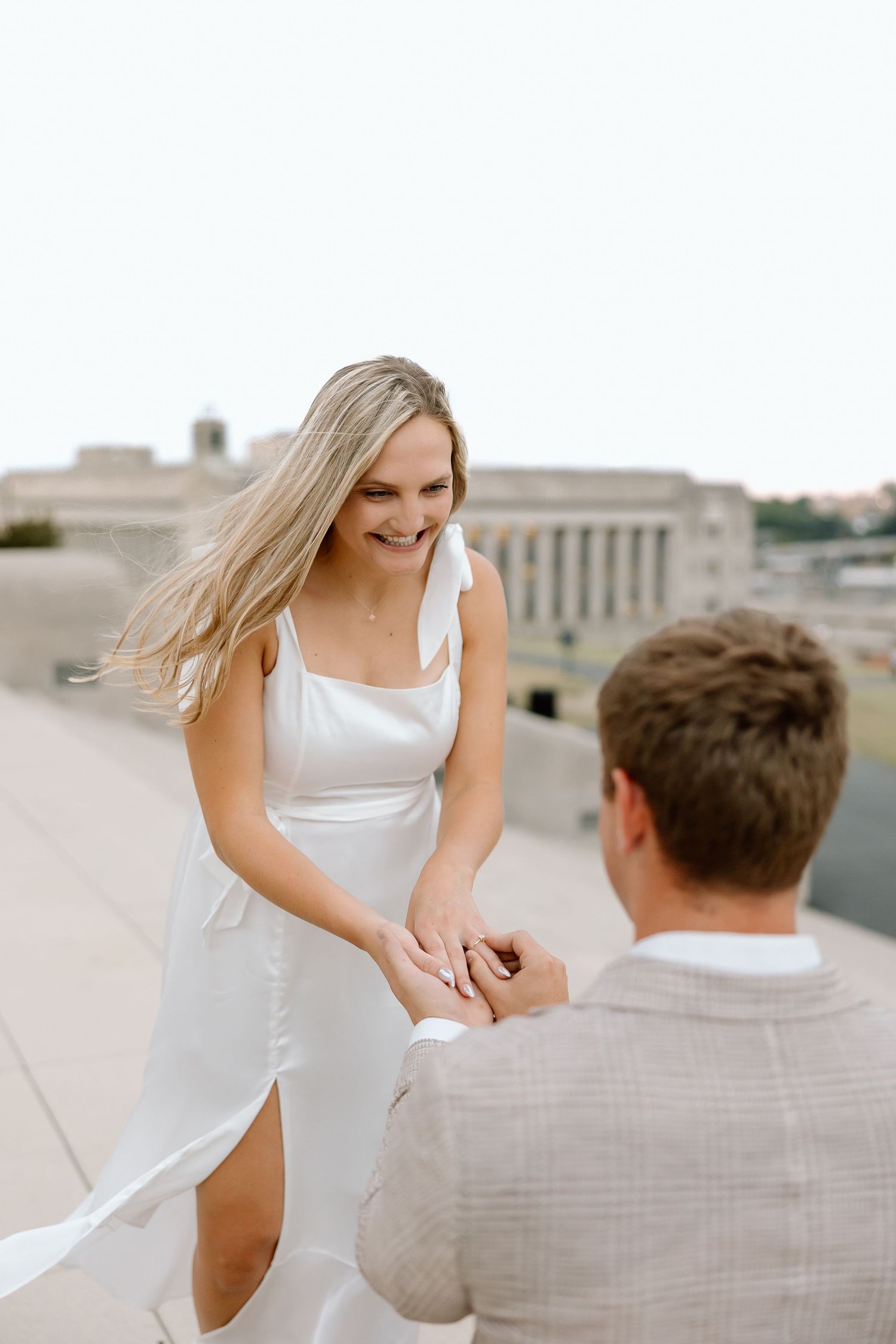 A couple shares a joyful moment during their engagement photoshoot at a grand historic building.