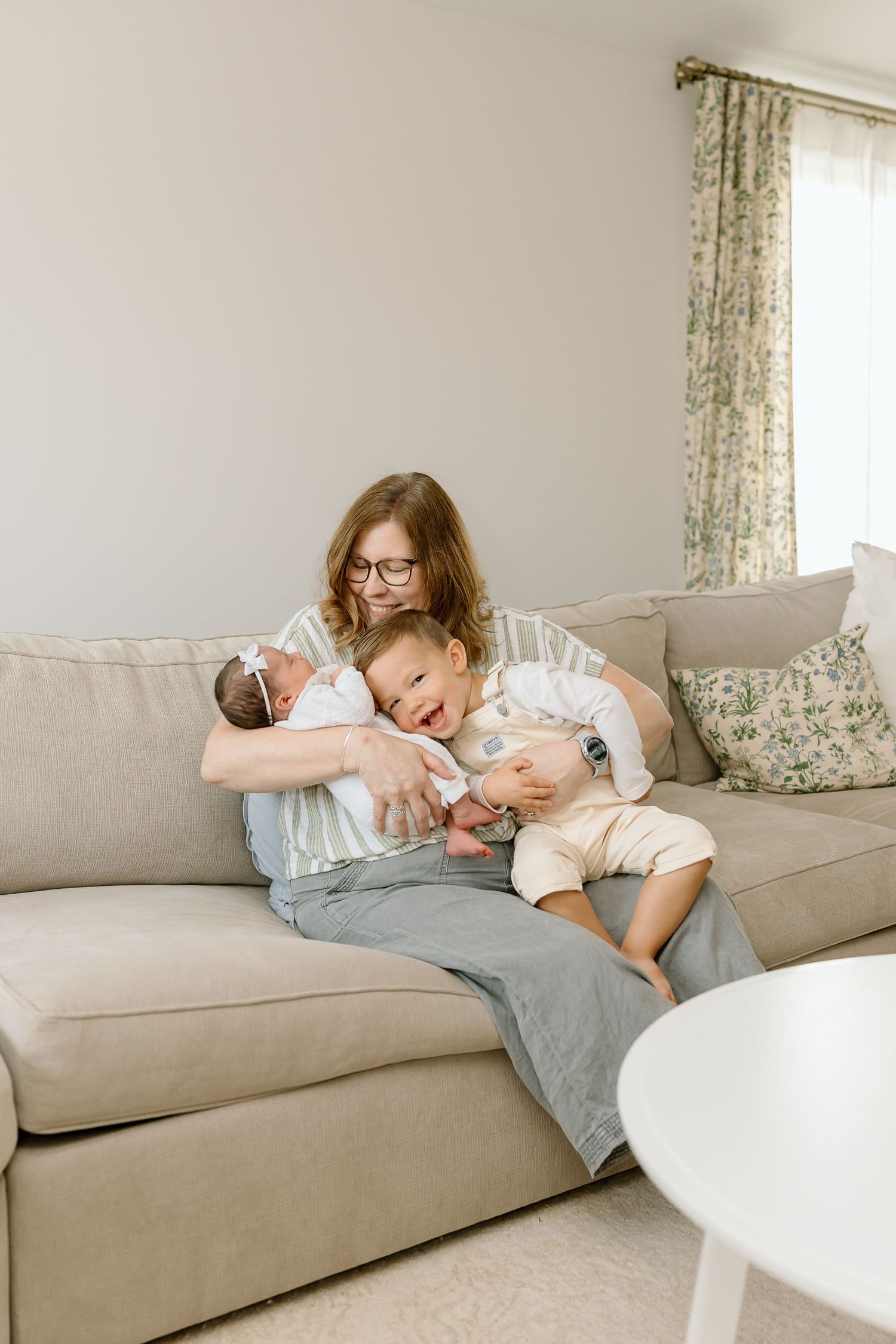 Three connected photos show a tender moment of rest and bonding on a beige couch in a bright, airy living room.