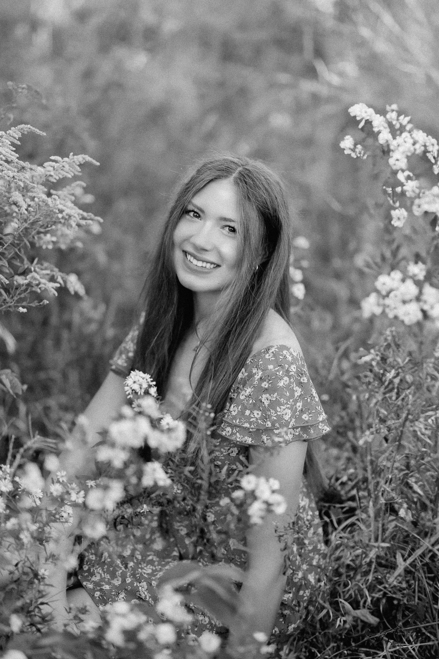 Black and white portrait series of a woman surrounded by delicate white wildflowers in a dreamy outdoor setting.