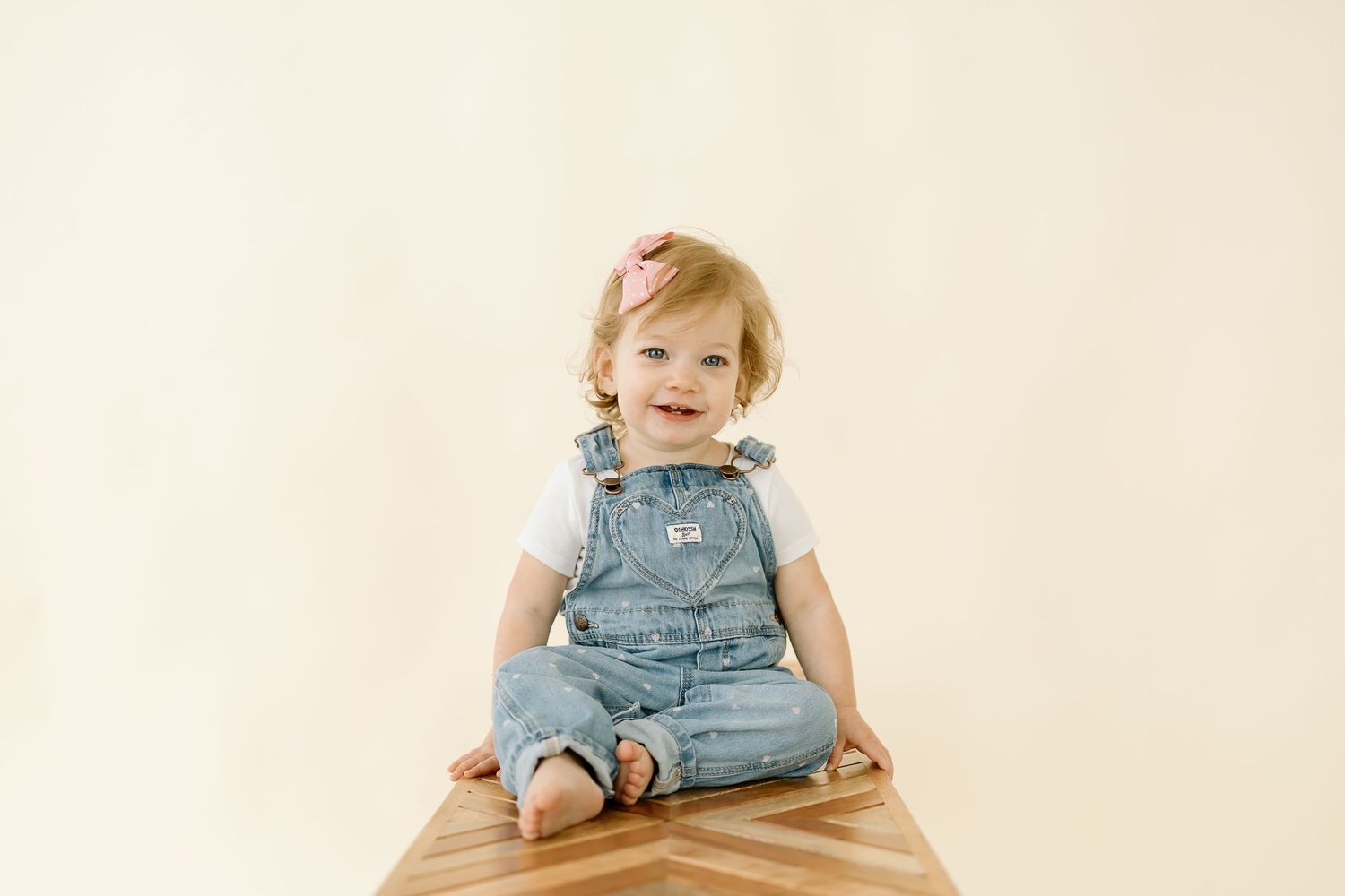 A baby in denim overalls sits and smiles while playing in a series of progressive action shots.