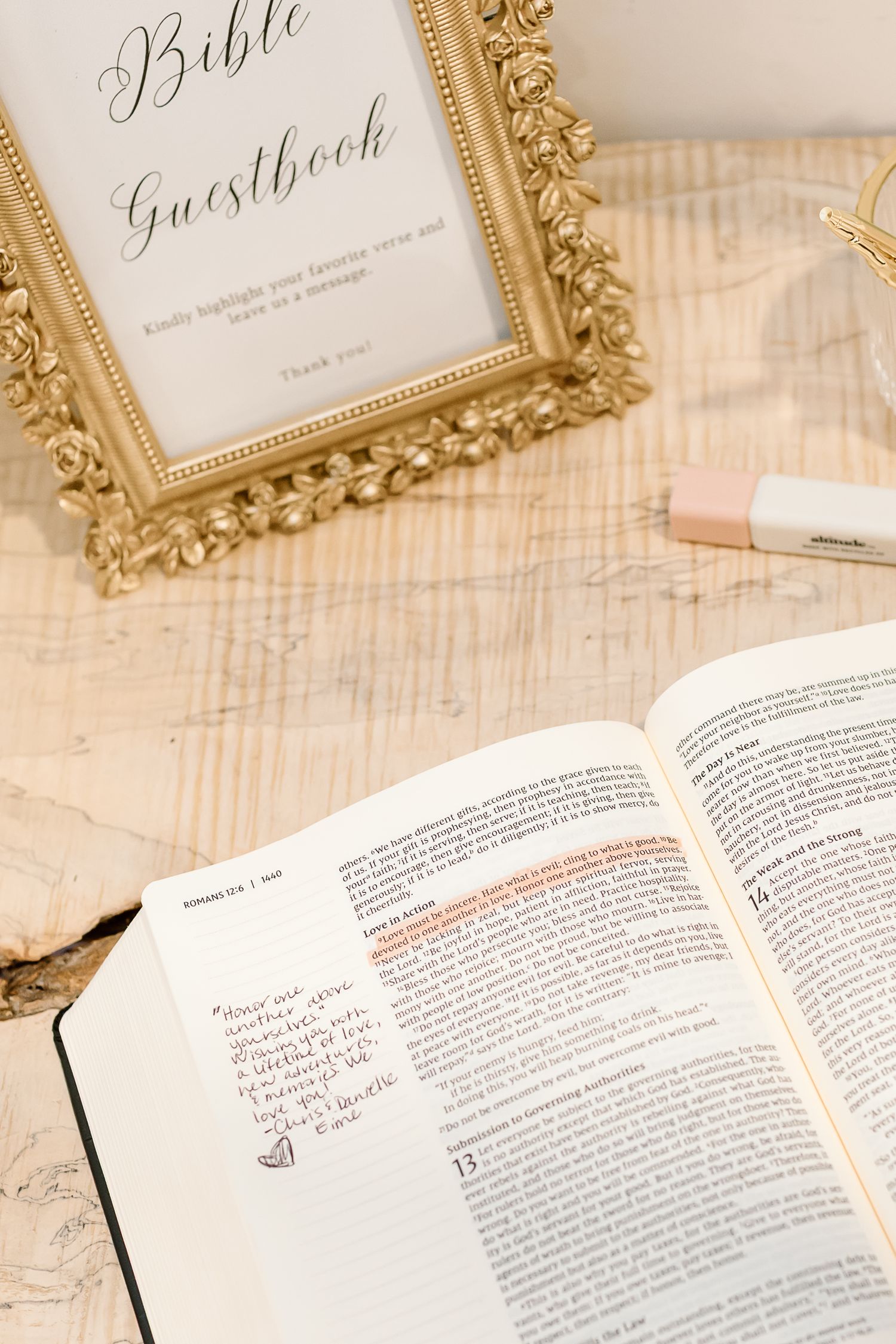 Ornate gold frames display wedding signage above an open Bible with handwritten notes on its pages.