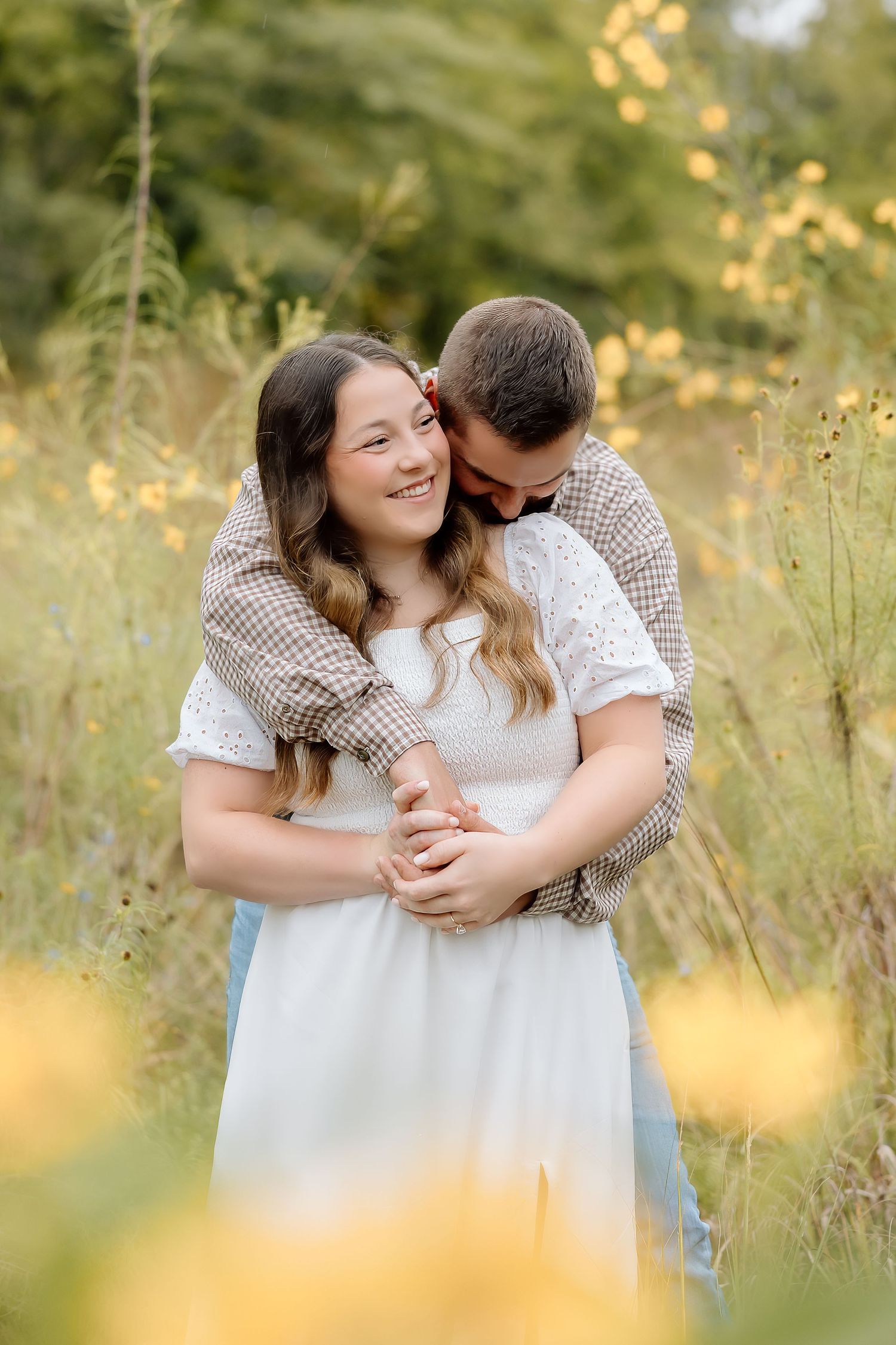 A tender moment shared between a couple in a sunlit meadow with yellow flowers.