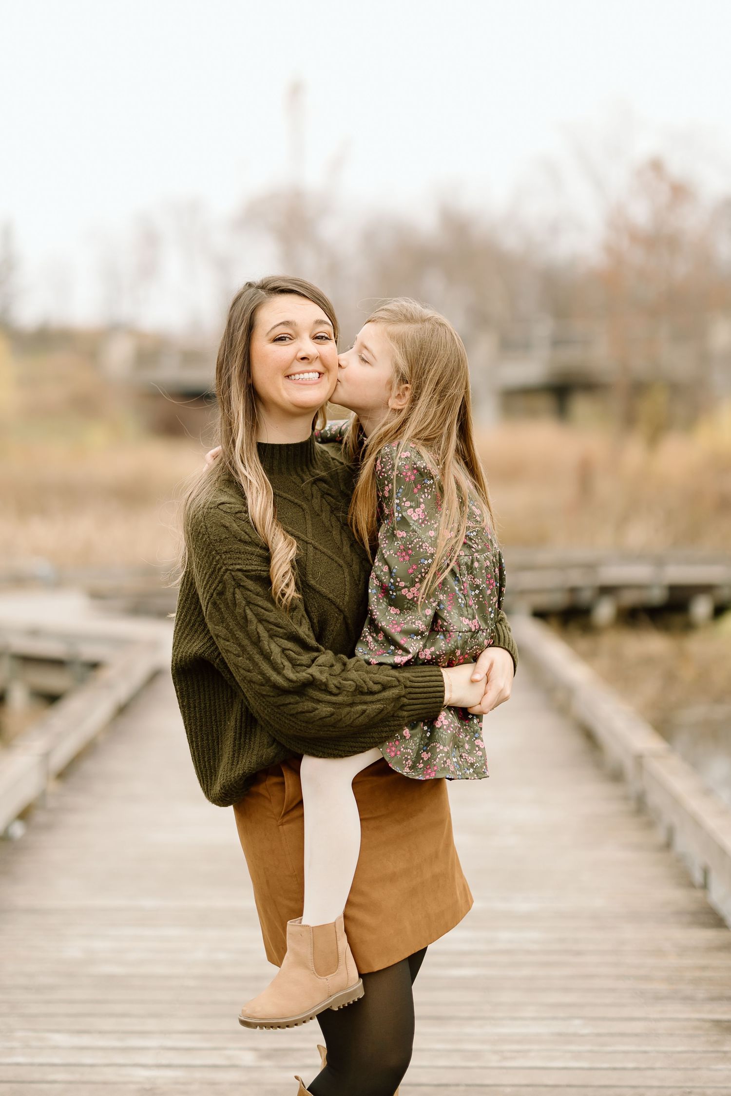 Candid moment of affection captured on a wooden walkway during an autumn photoshoot.