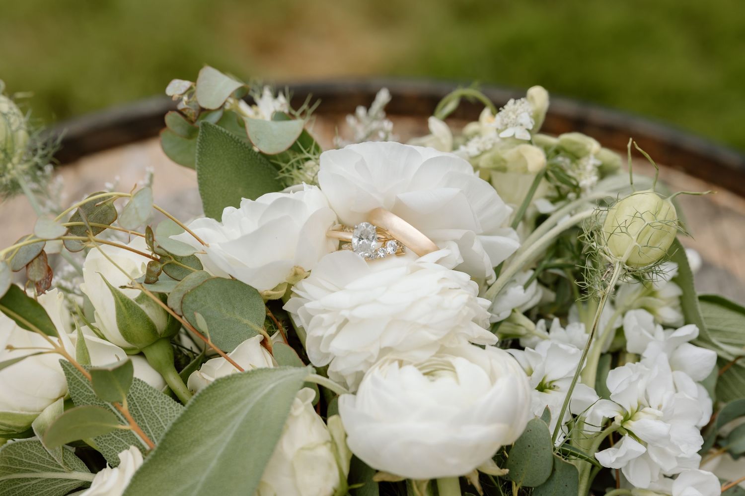 Wedding rings nestled in a white peony bouquet with eucalyptus and delicate white blooms.