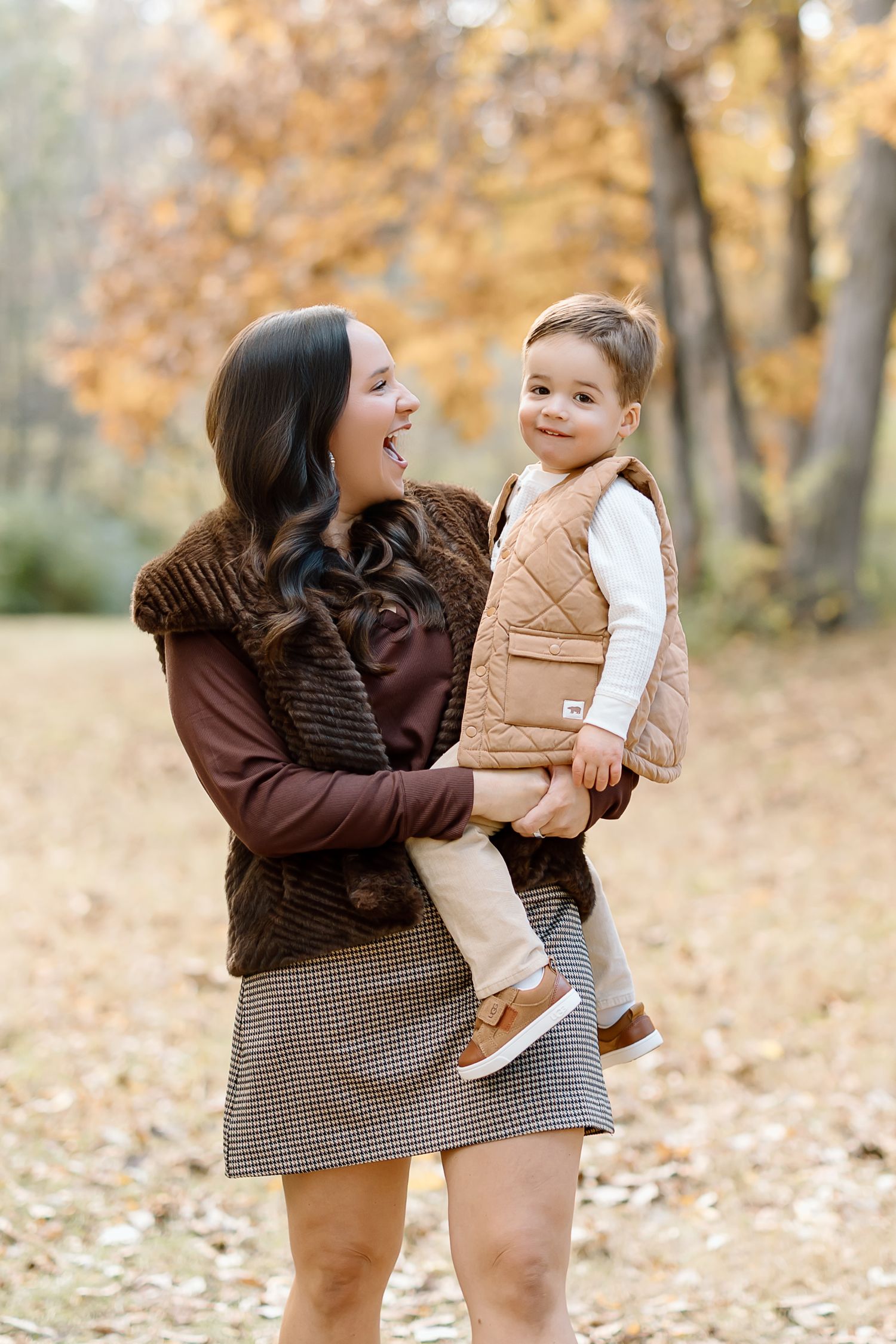 A tender moment shared between parent and child in an autumn forest setting with golden leaves on the ground.