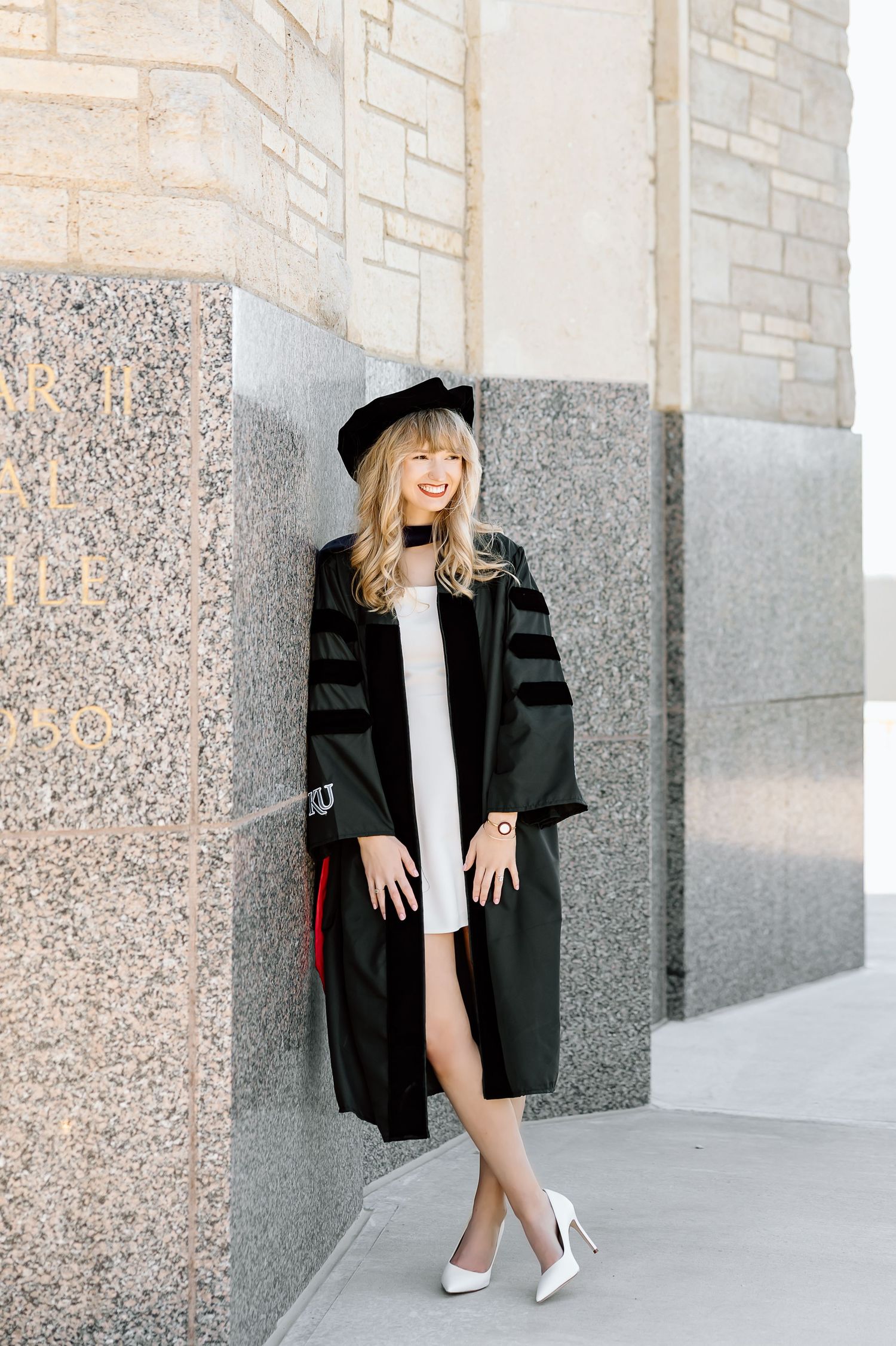 A person in a black blazer and white dress poses against a stone wall in three stylish fashion shots.