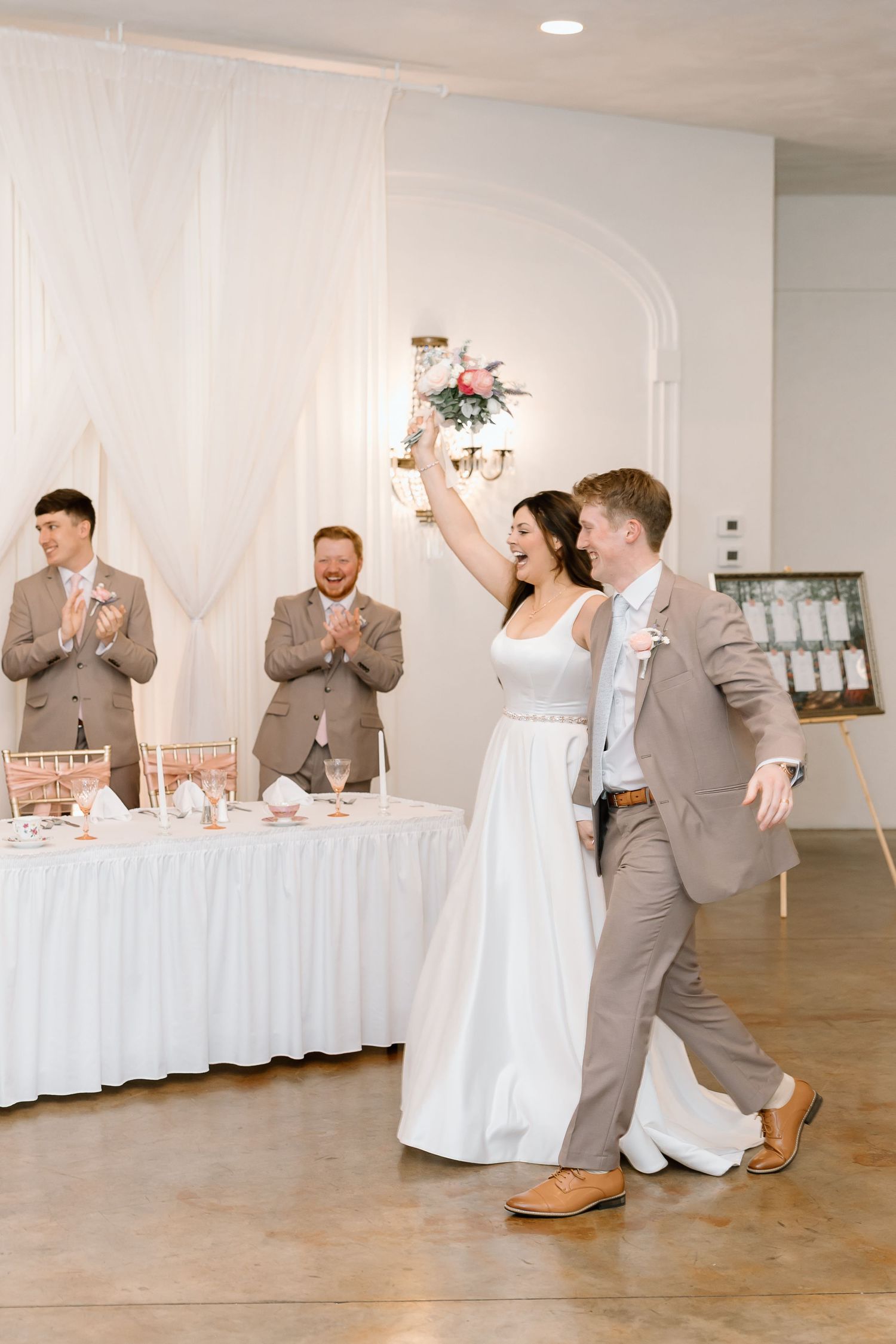 A wedding party performs a fun choreographed dance sequence in a white reception hall.
