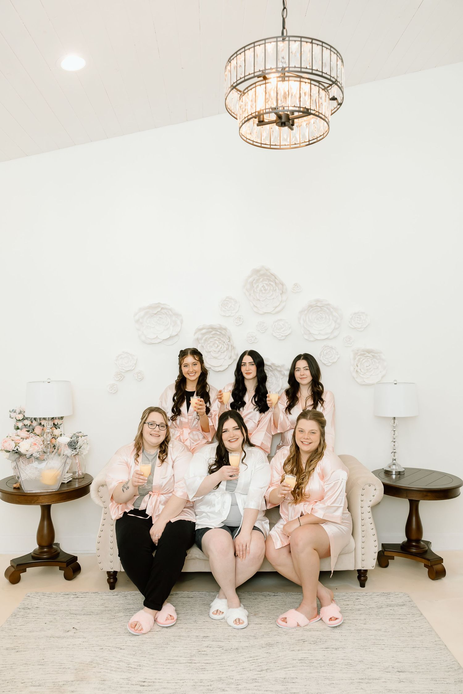 Group seated together on a light carpet in a bright white room with elegant chandelier lighting.