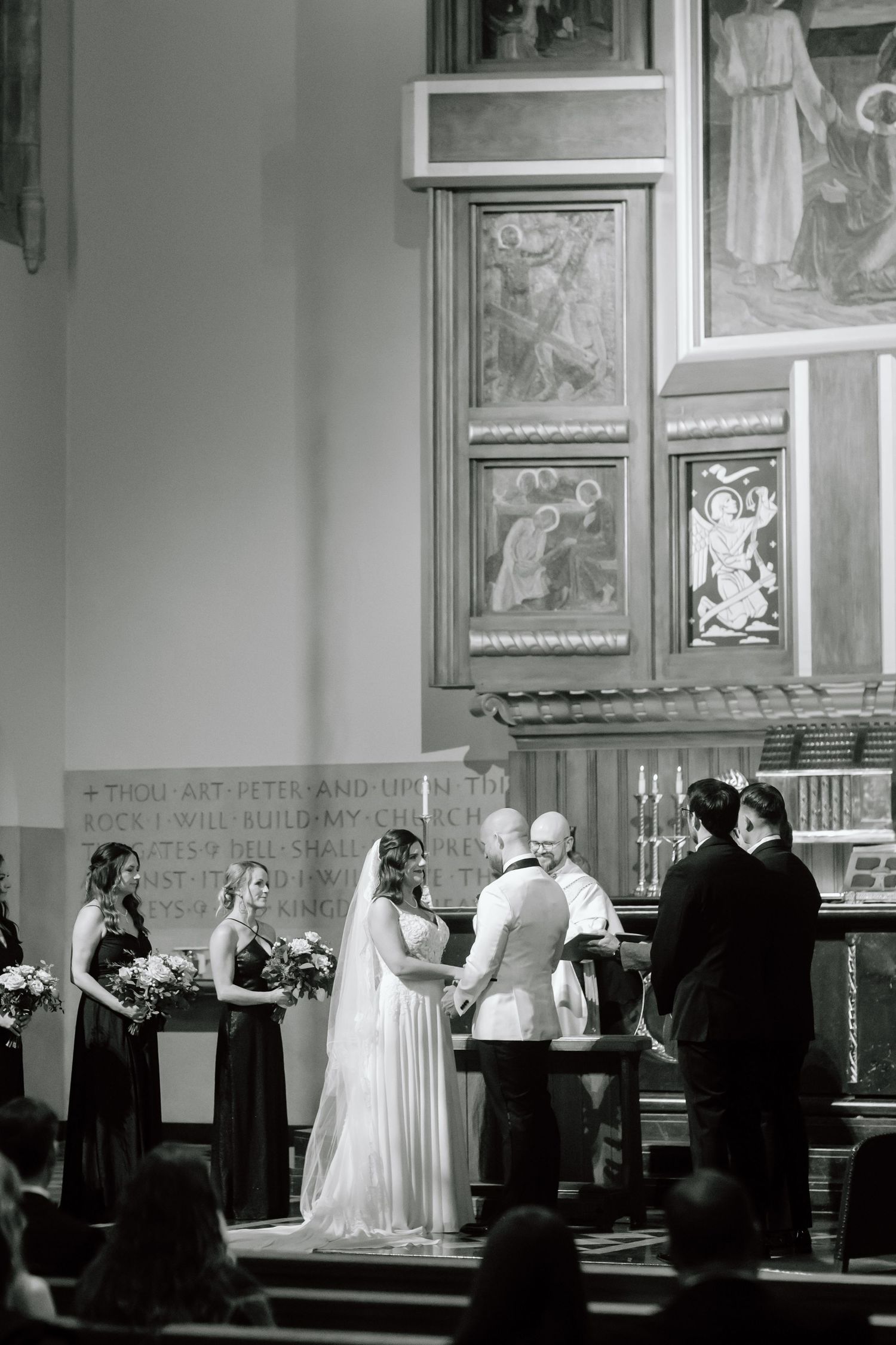 Black and white panoramic photograph of a wedding ceremony taking place in a church with ornate decorative walls.