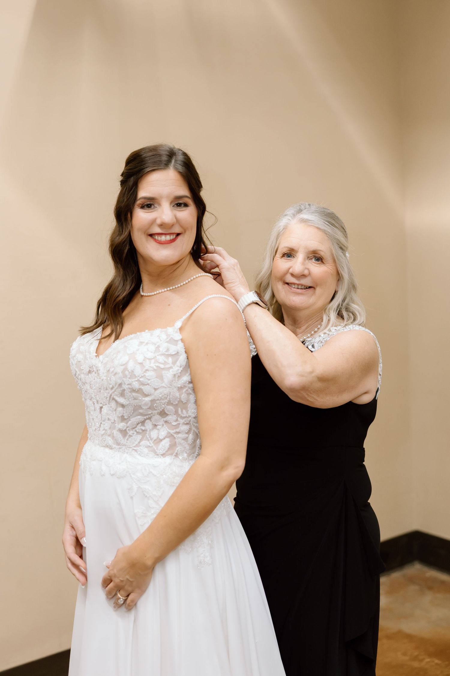 A person in a flowing white lace wedding dress poses with someone wearing black in multiple similar shots.