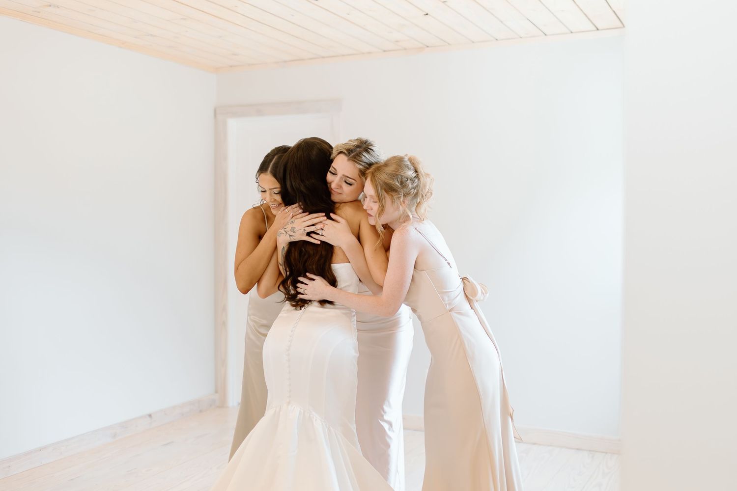 A bride in a flowing white wedding dress twirls gracefully in a bright sunlit room with white walls.