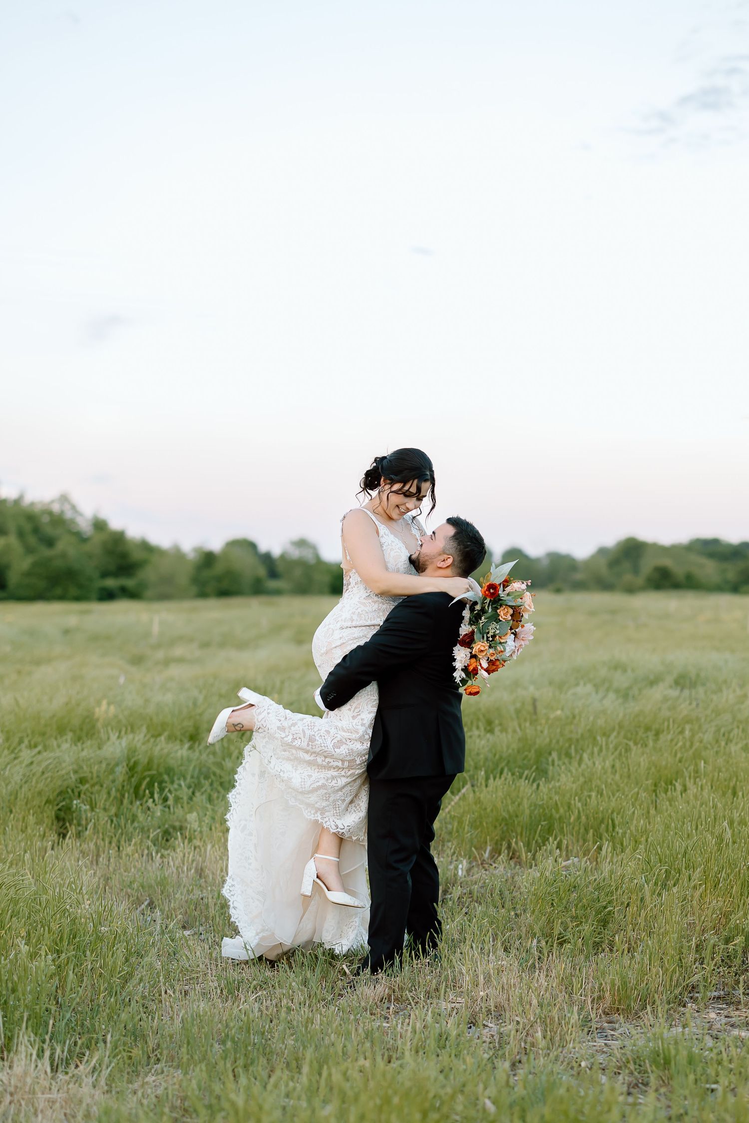 Romantic couple sharing a passionate embrace in a serene meadow during their wedding day celebration.