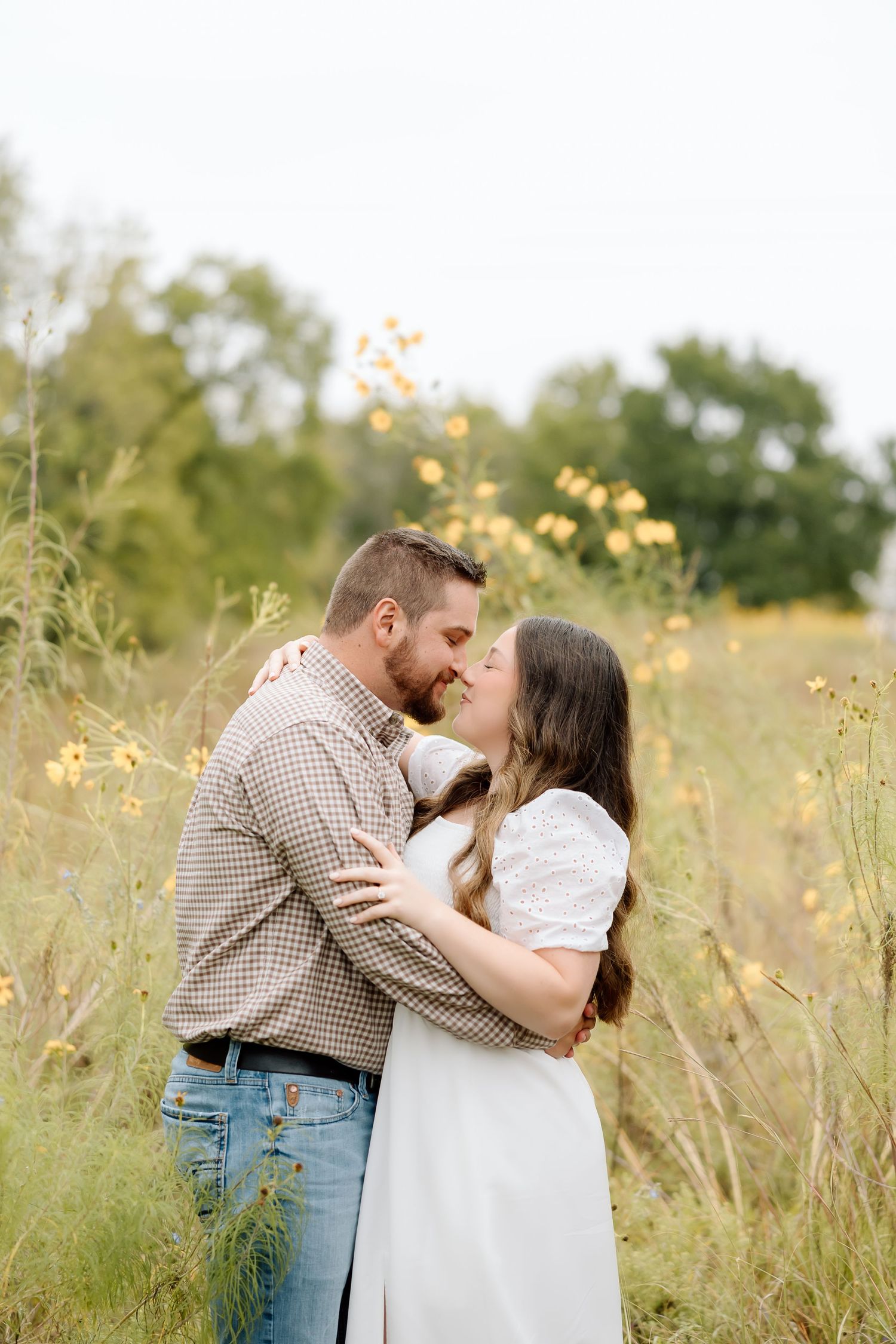 A couple shares an intimate moment while standing in a field of wildflowers during golden hour.