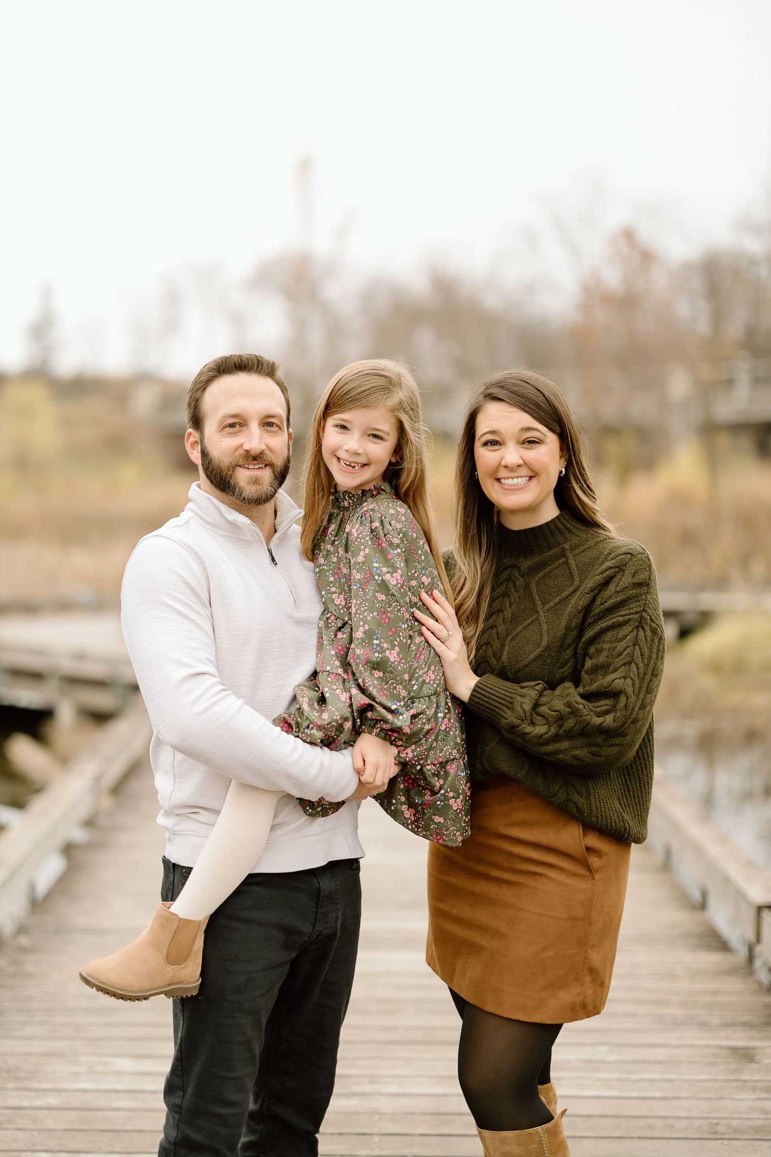 Happy family portrait on rustic boardwalk during autumn season.