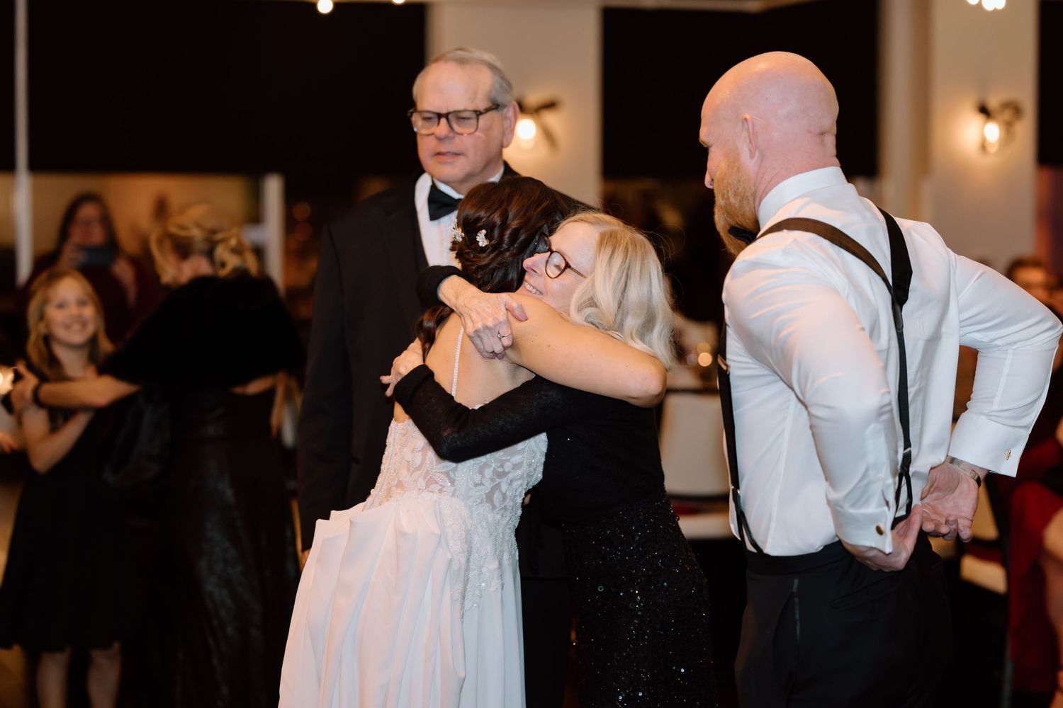 Couples dance together at an elegant wedding reception in a warmly lit ballroom.