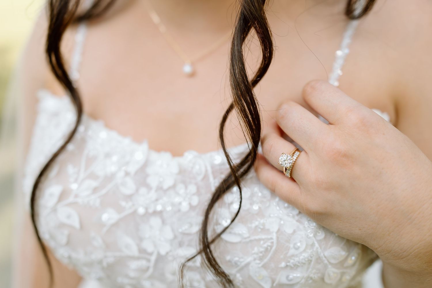 A close-up detail shot of a white lace wedding dress with delicate floral embroidery patterns.