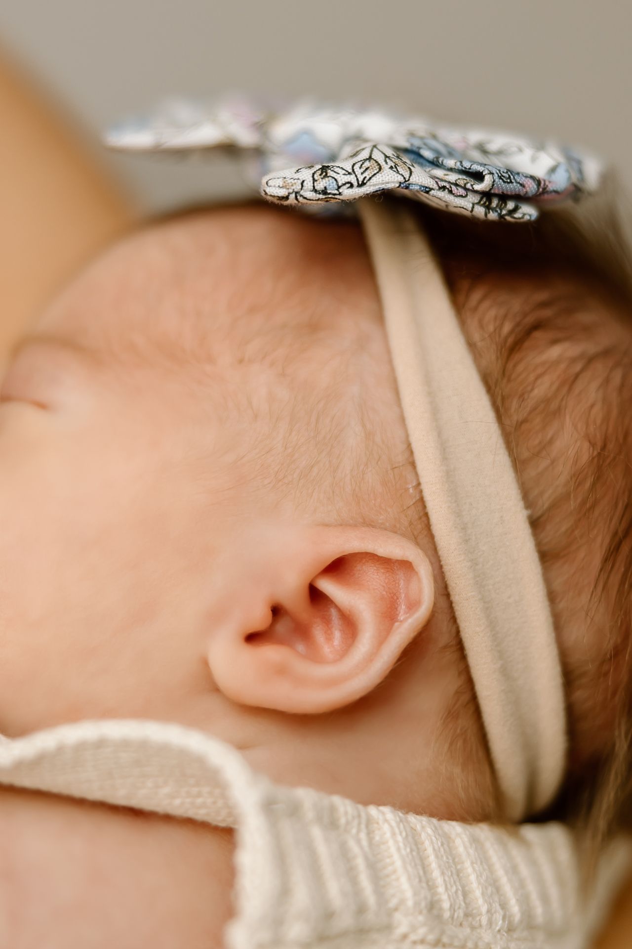 Detailed shot of a baby's ear and headband showing intricate silver bow details.