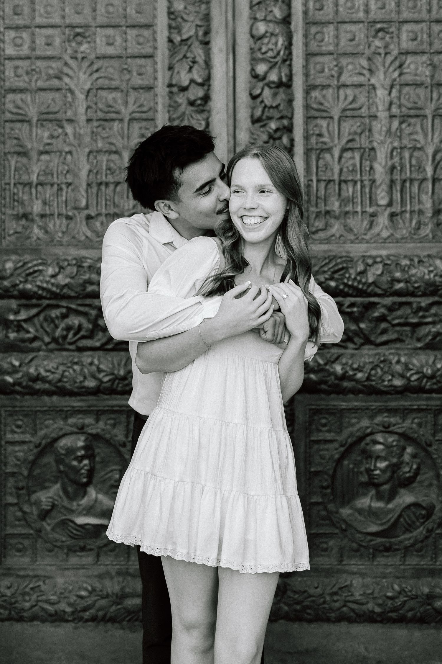 A series of black and white romantic photos showing a couple in white clothing embracing against a textured stone wall.