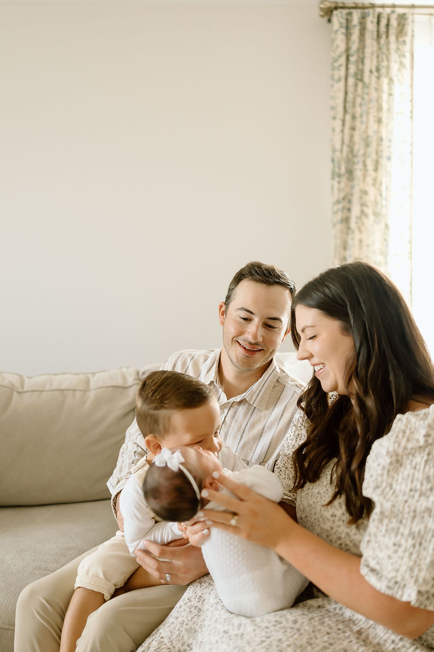Family shares joyful moments together on a light gray couch in a bright living room setting.