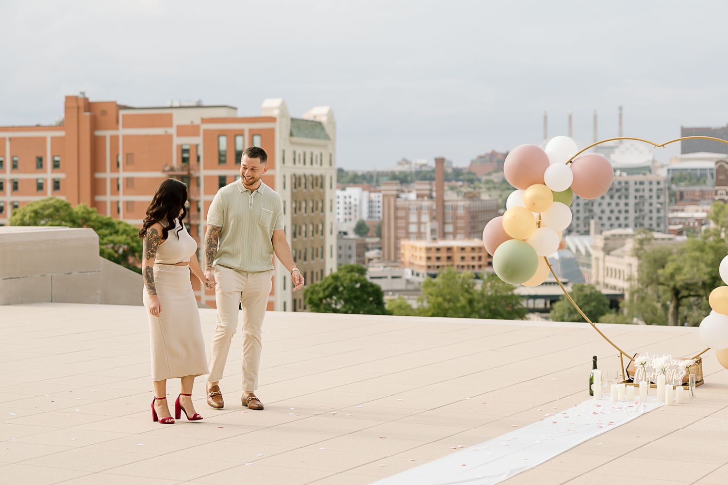 Urban rooftop terrace with white balloons and city buildings visible in the background.
