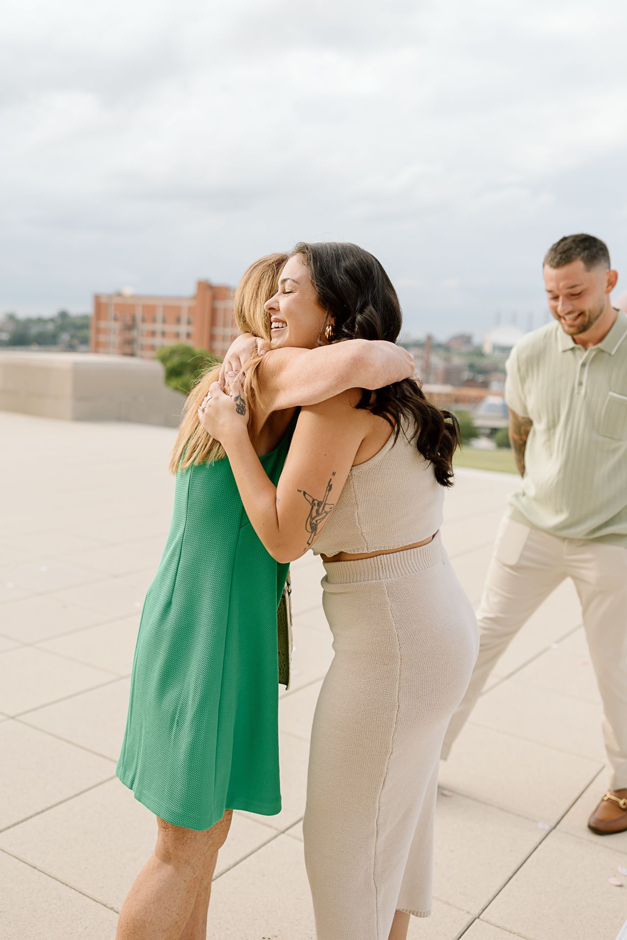A couple sharing a joyful moment on a rooftop terrace during what appears to be a surprise proposal.
