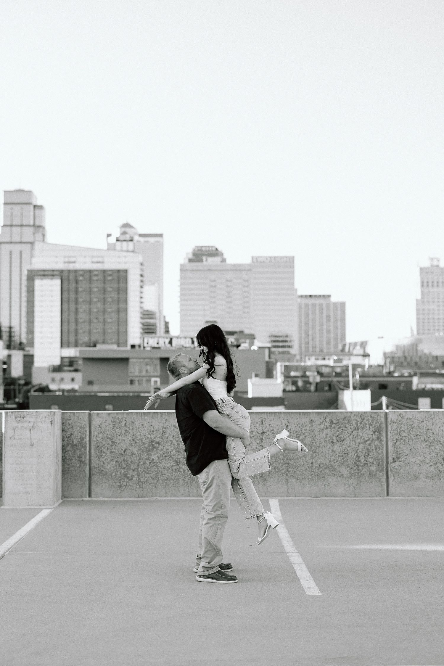 A sequence of four black and white photos showing a person performing parkour moves on an urban rooftop with a city skyline.