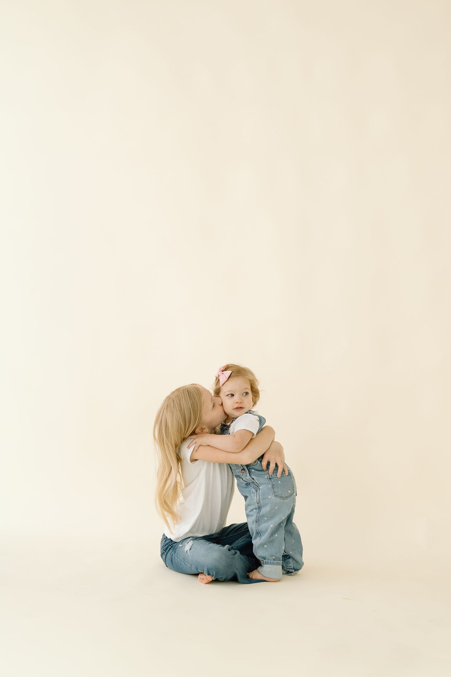 A minimalist photo series showing two children sitting together on a white background in various casual poses.