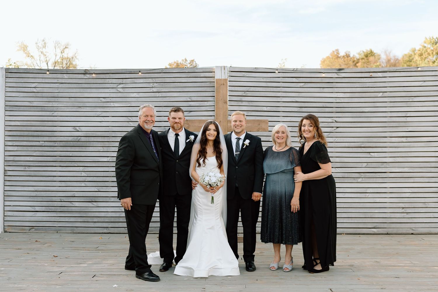 Wedding party poses in front of corrugated metal wall in various creative group formations.