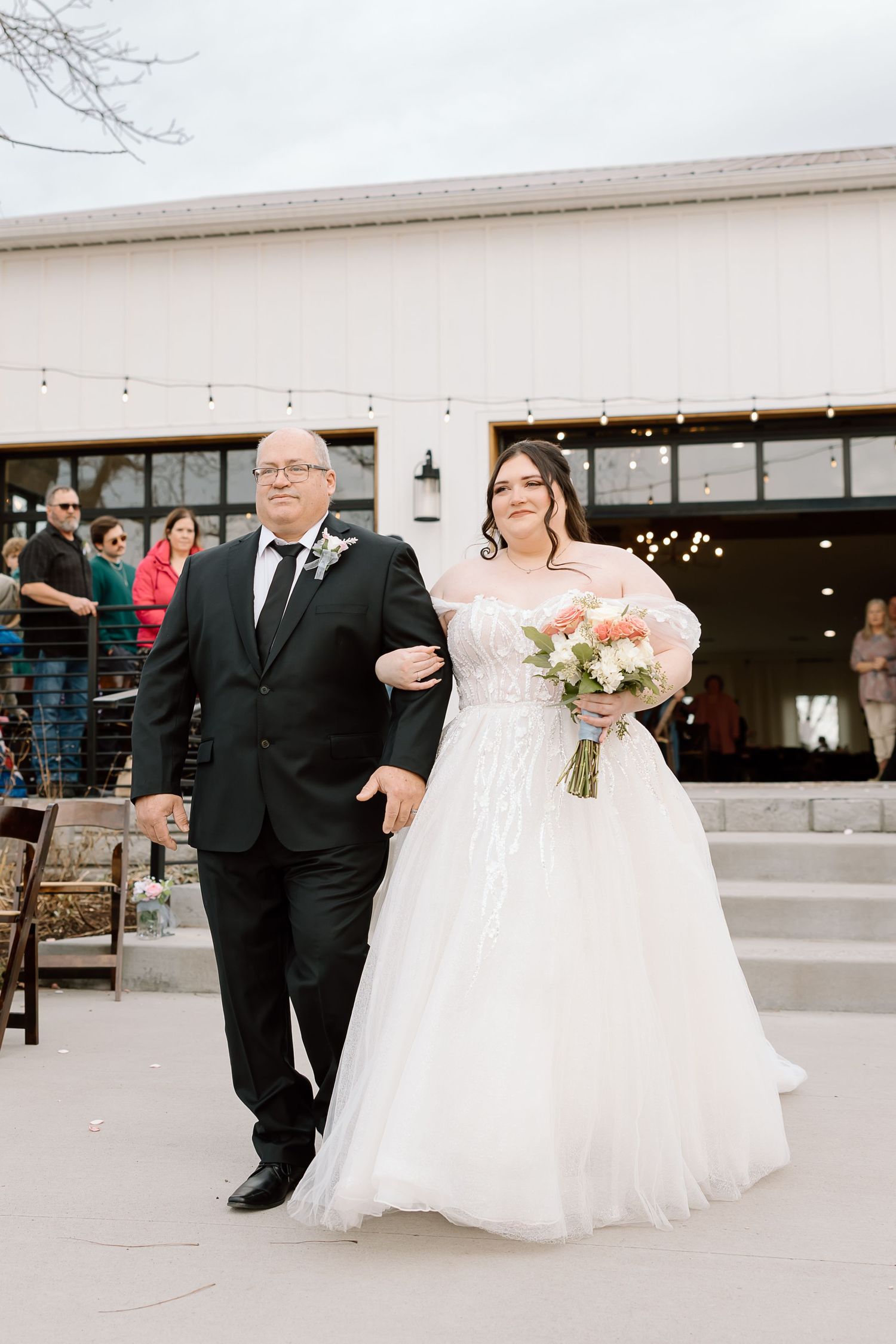 A couple in formal wedding attire walking together on a light colored floor during their celebration.
