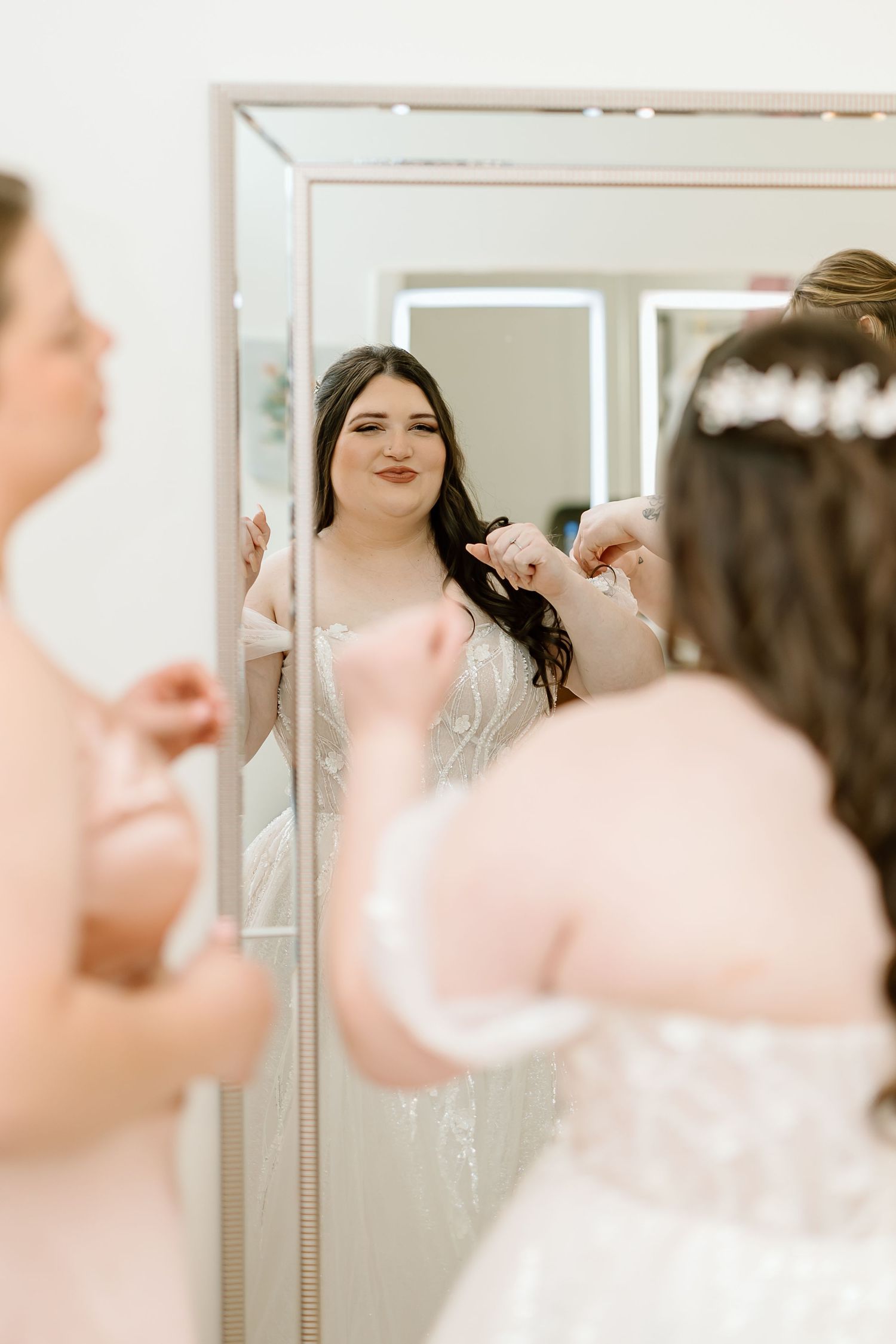 Two people looking at their reflections in a series of mirrors in a bright white room.