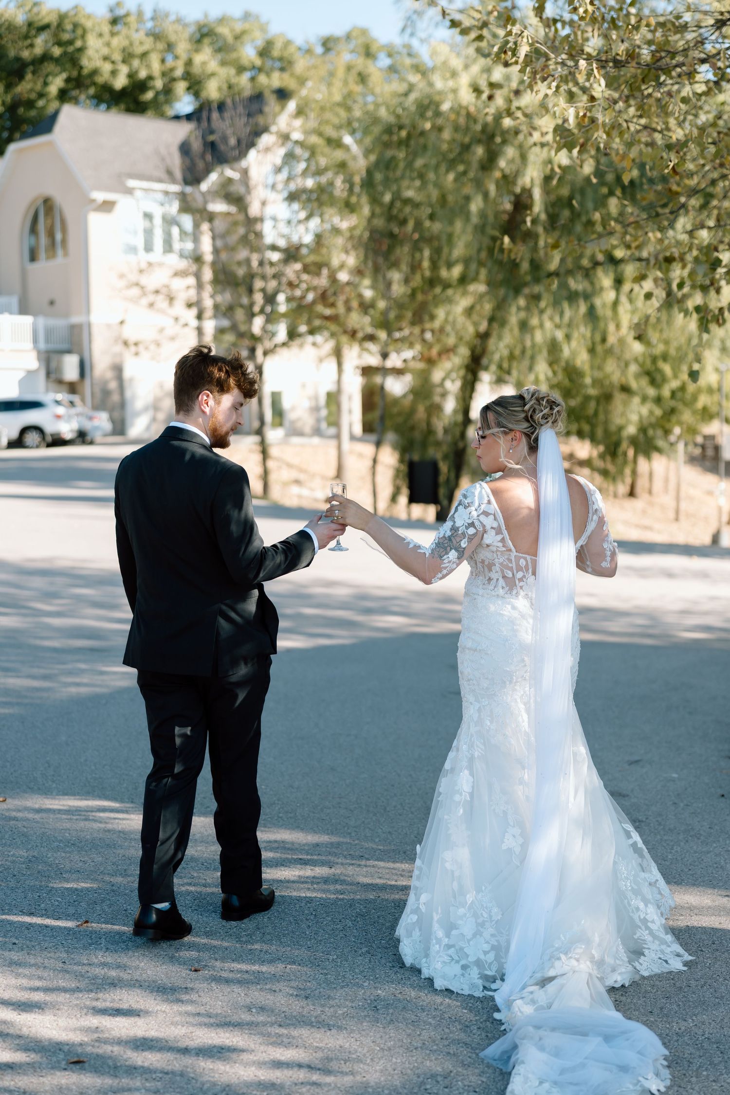 A newlywed couple dances joyfully in a parking lot, with the bride's dress swirling around them.