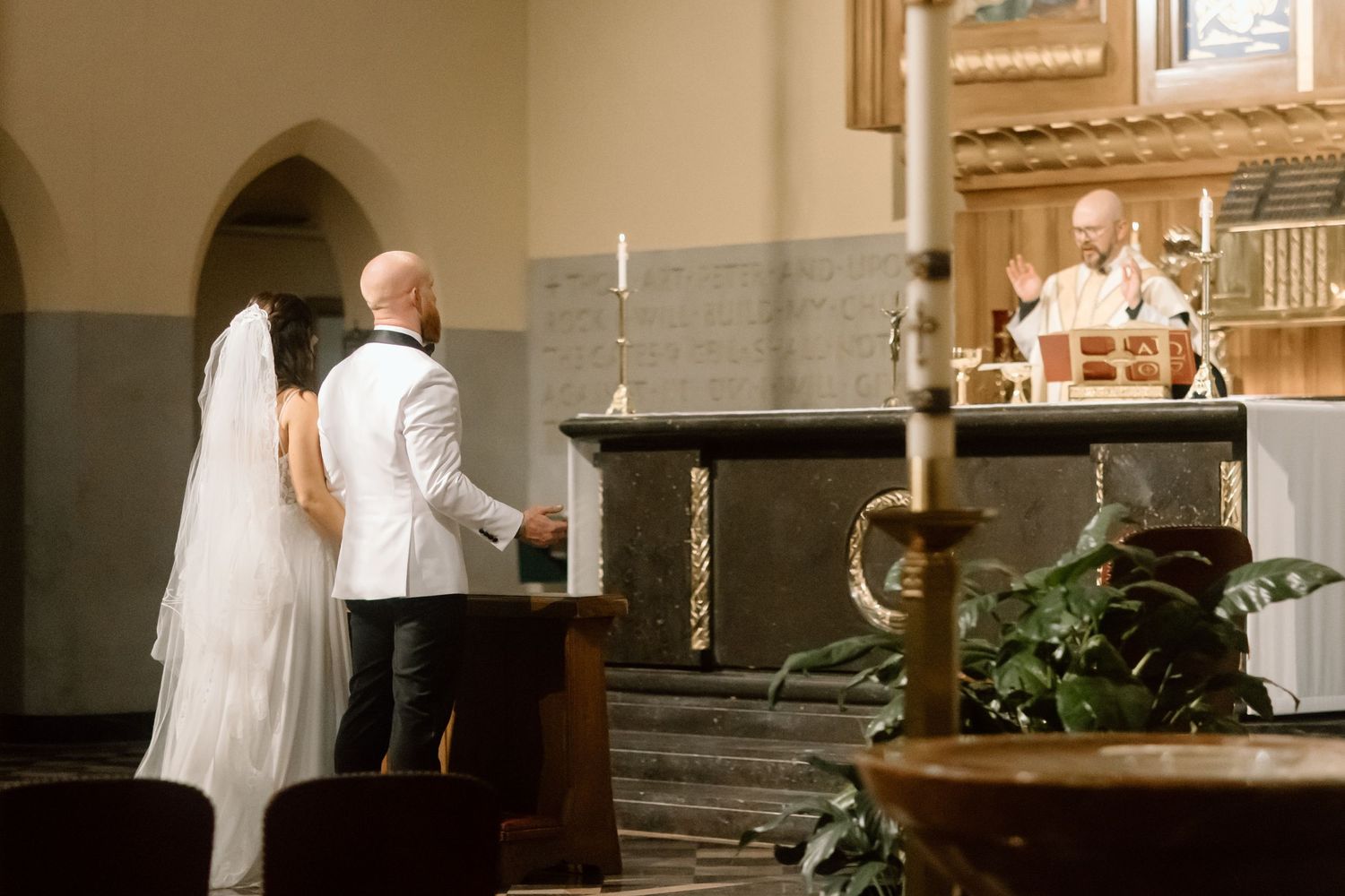 A couple stands at the altar during their wedding ceremony in a traditional church setting.