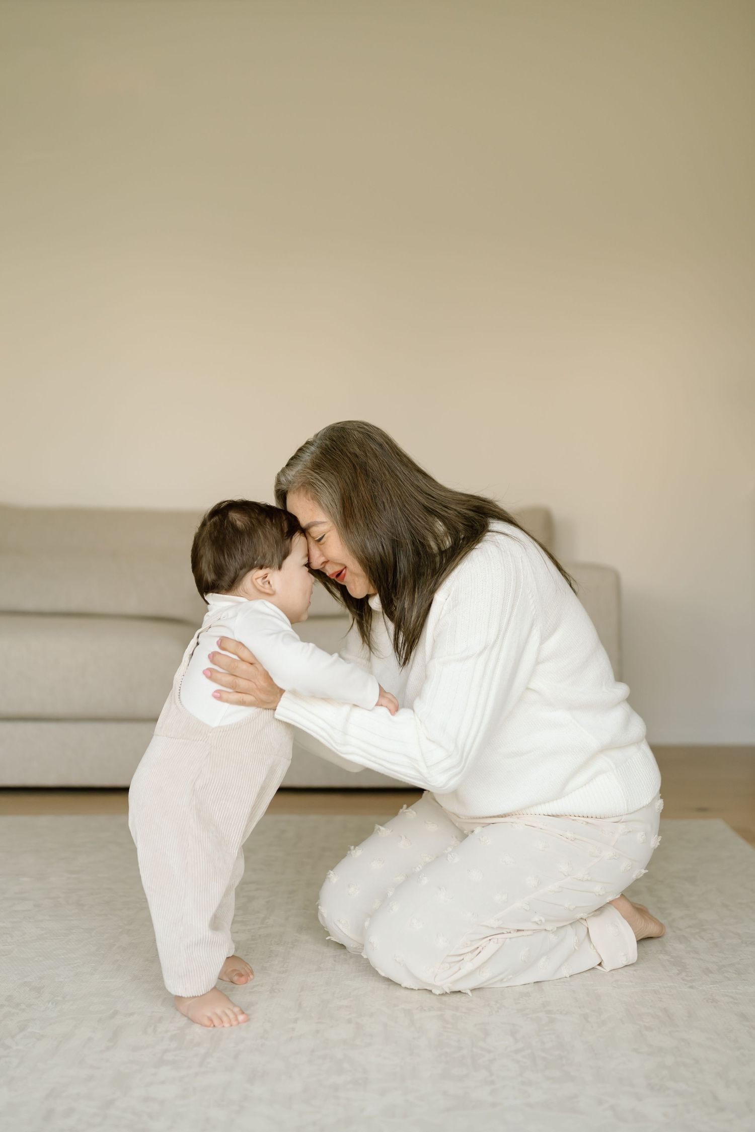 Two people in white clothing practicing yoga poses together on a light gray carpet.
