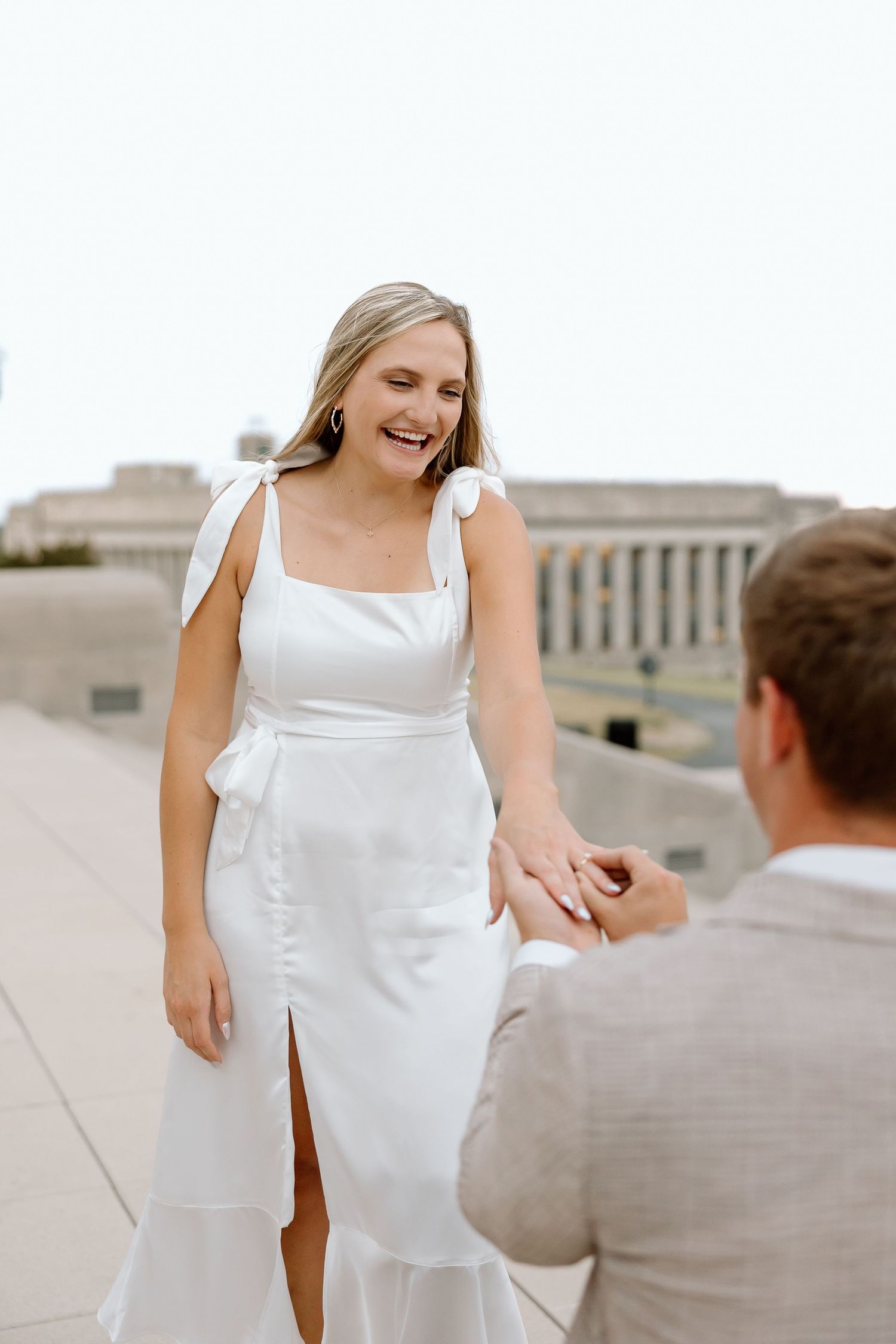 A joyful couple in wedding attire share a candid moment together on a rooftop terrace.