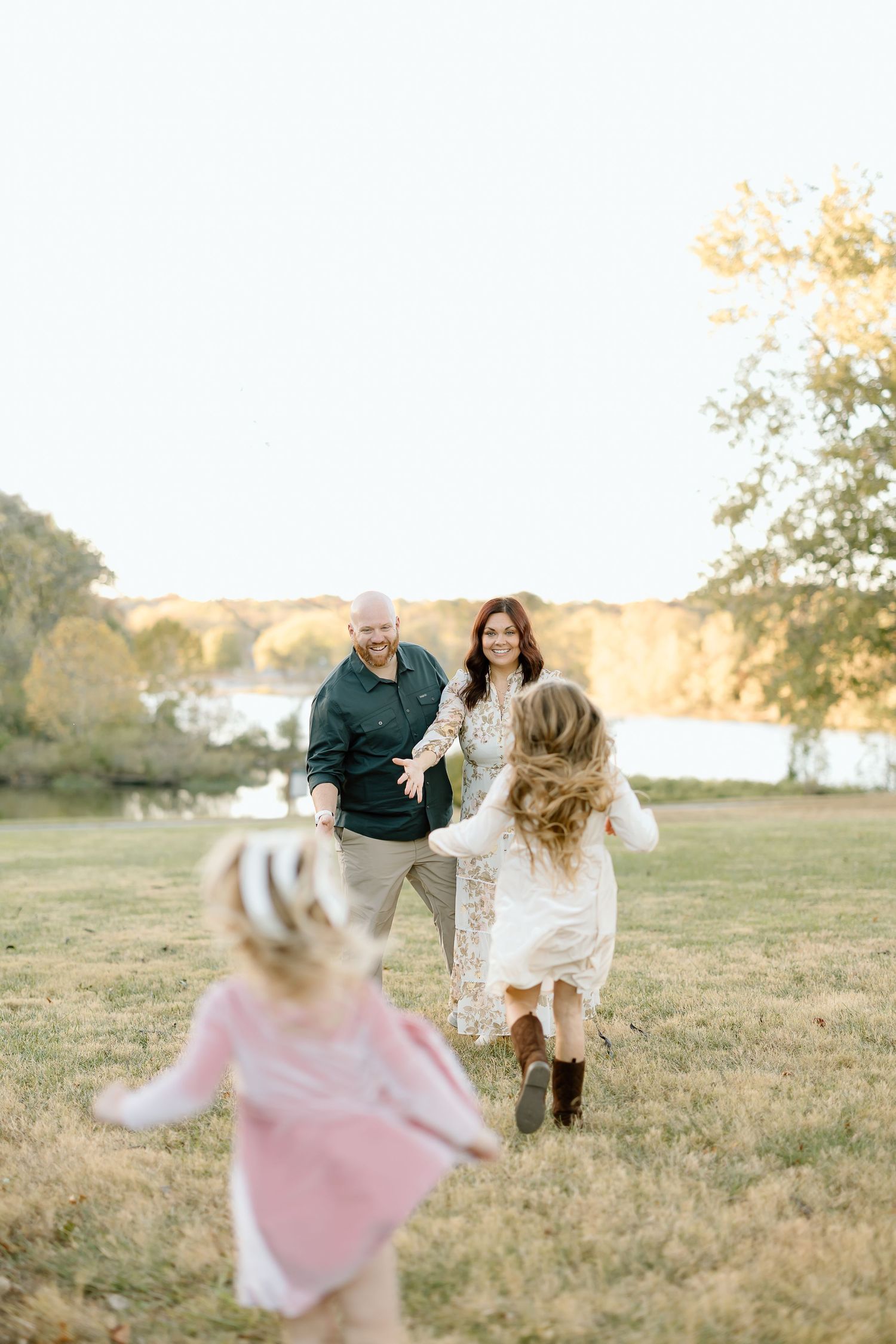 Family running and playing together in a golden sunlit field during a warm autumn evening.