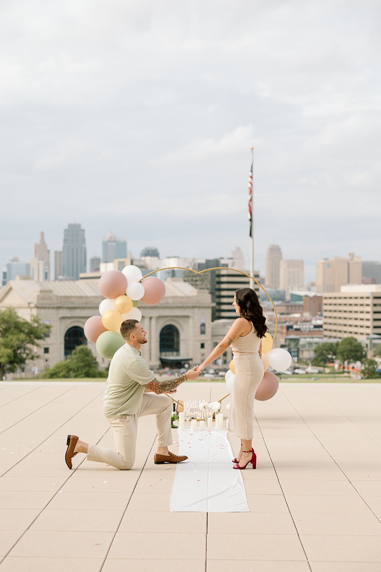 A couple performs a romantic dance sequence on a rooftop with a city skyline in the background.
