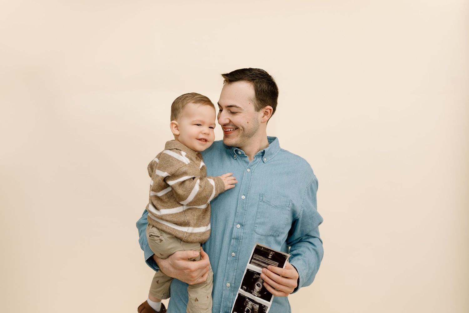 A parent in a blue shirt holds a laughing toddler wearing a beige sweater in a series of candid moments.