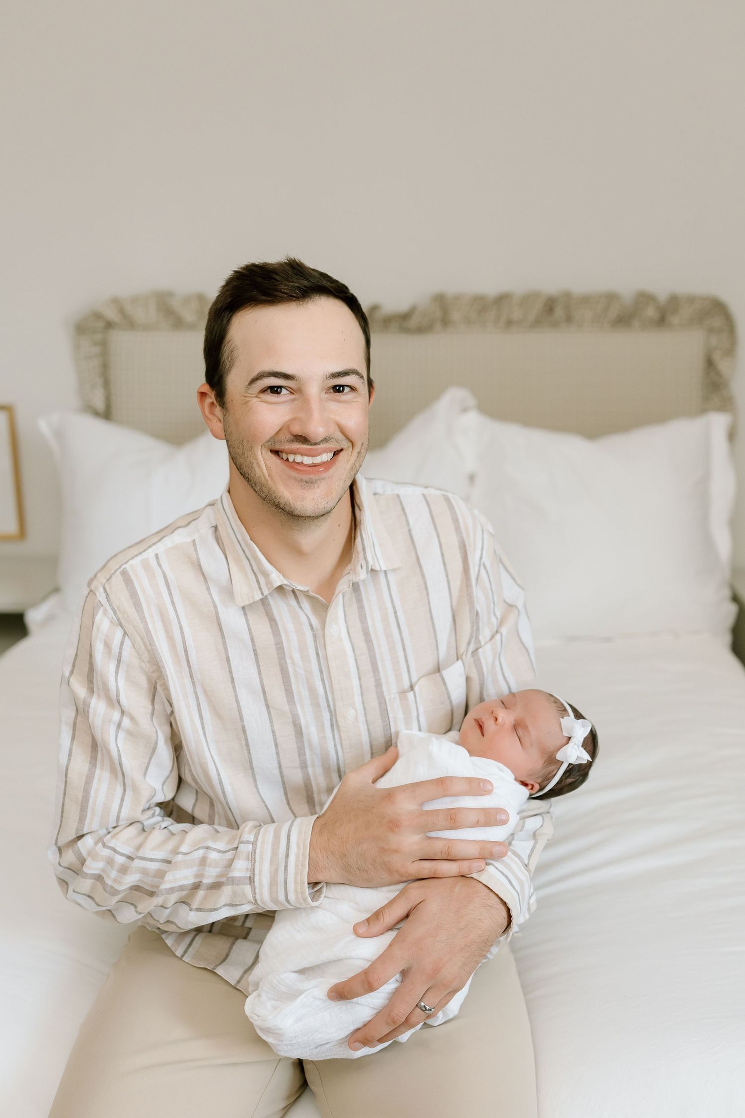 A series of tender moments showing someone holding a newborn baby while sitting on a white bed.