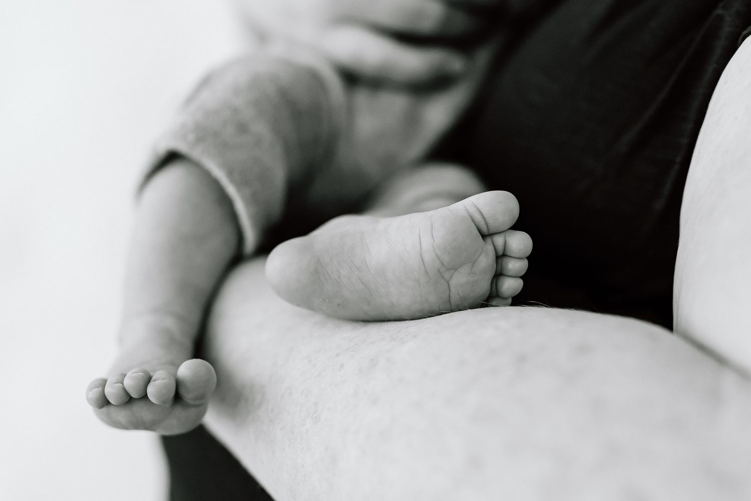 Black and white photo series showing a newborn baby's tiny feet, hands and delicate features.