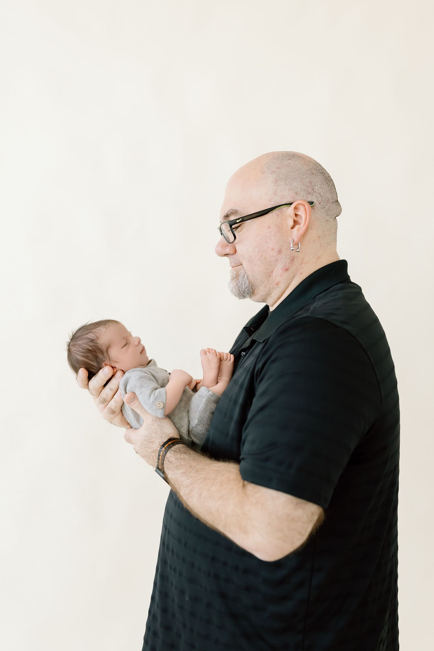 Three sequential images show a person in black holding and cradling a small baby against their chest.
