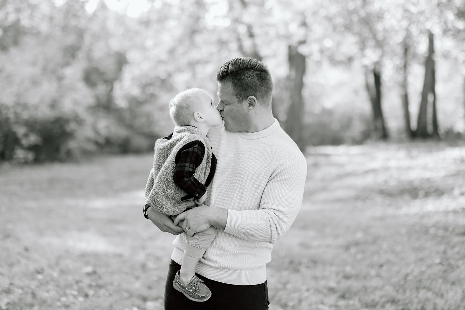 Black and white photo of tender parental moment in a natural outdoor setting.