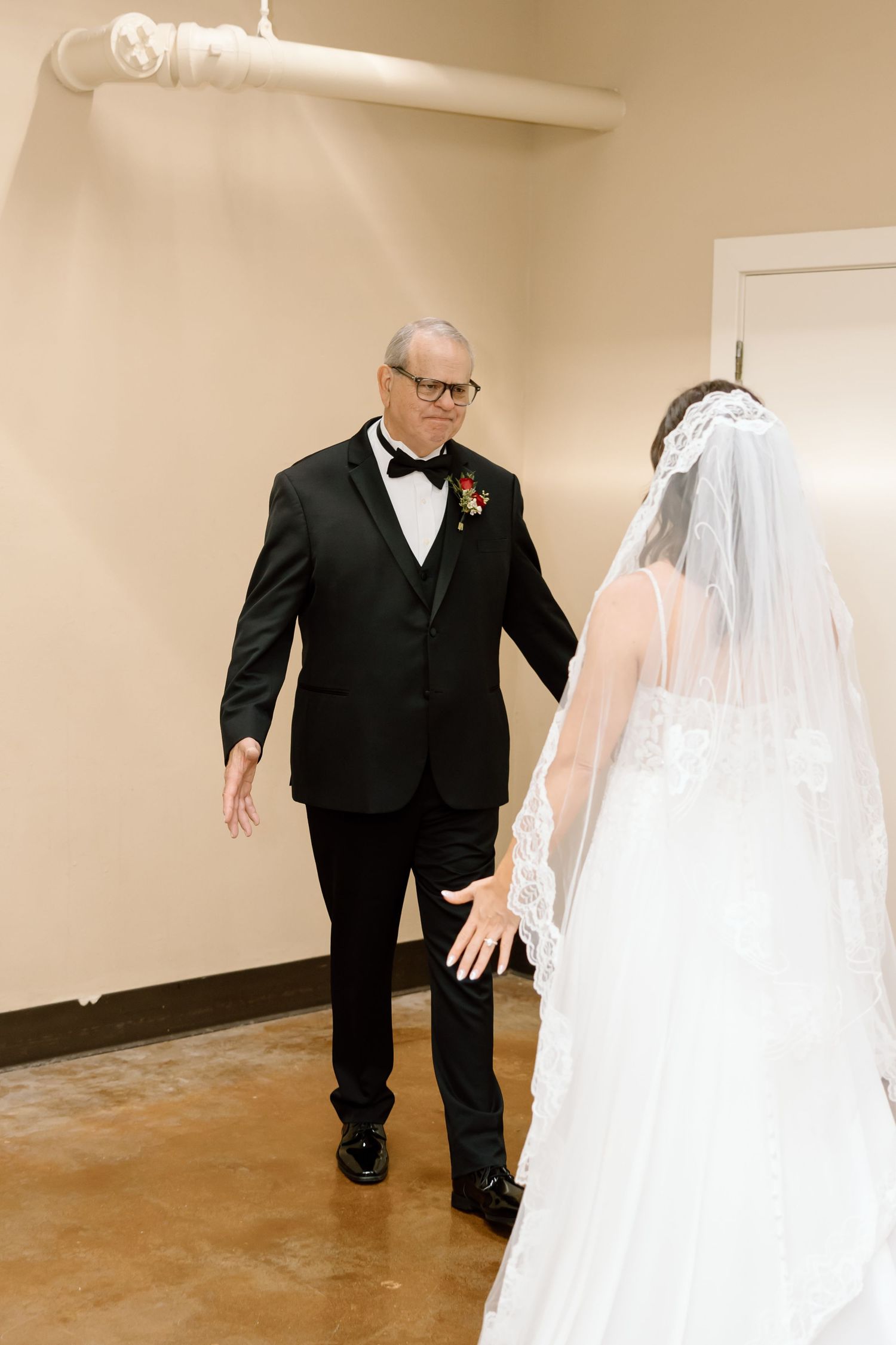 A touching moment as a bride in a white gown and veil shares a special moment with a man in a black tuxedo.